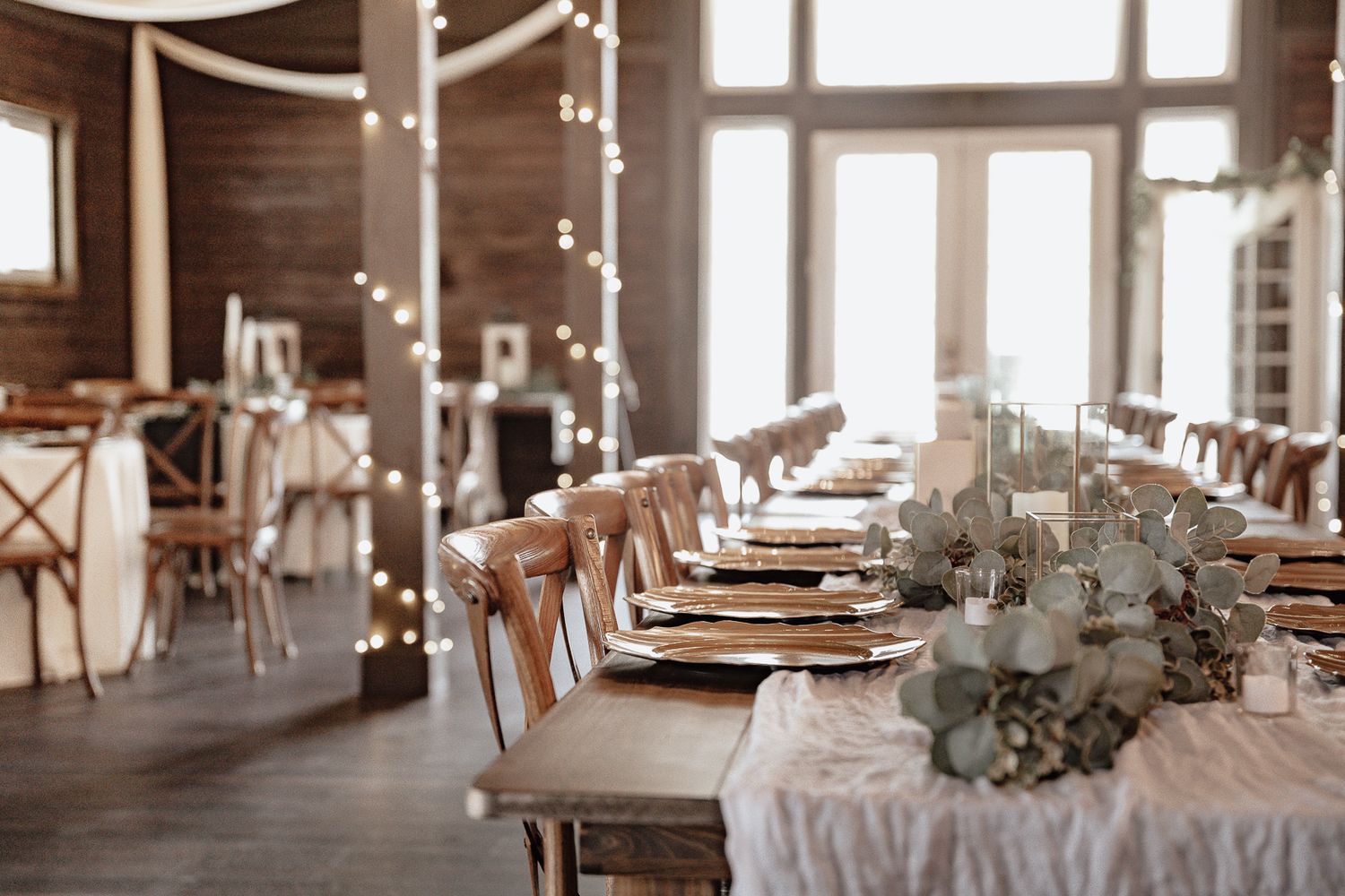 An elegant banquet hall decorated with white linens and floral centerpieces set for a formal wedding reception.