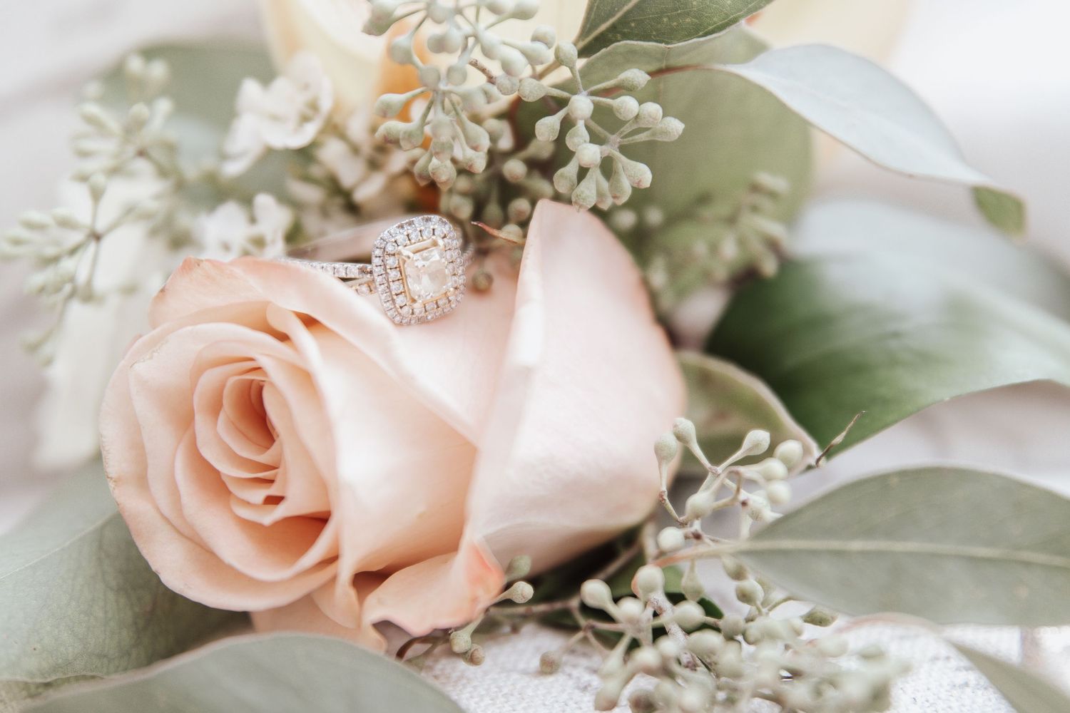 Delicate peach roses and greenery in romantic wedding floral arrangement.