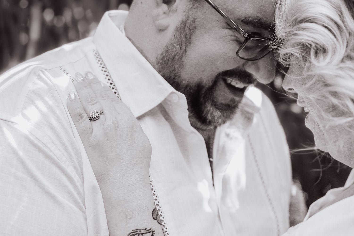 Black and white intimate portrait of couple sharing a tender moment outdoors.