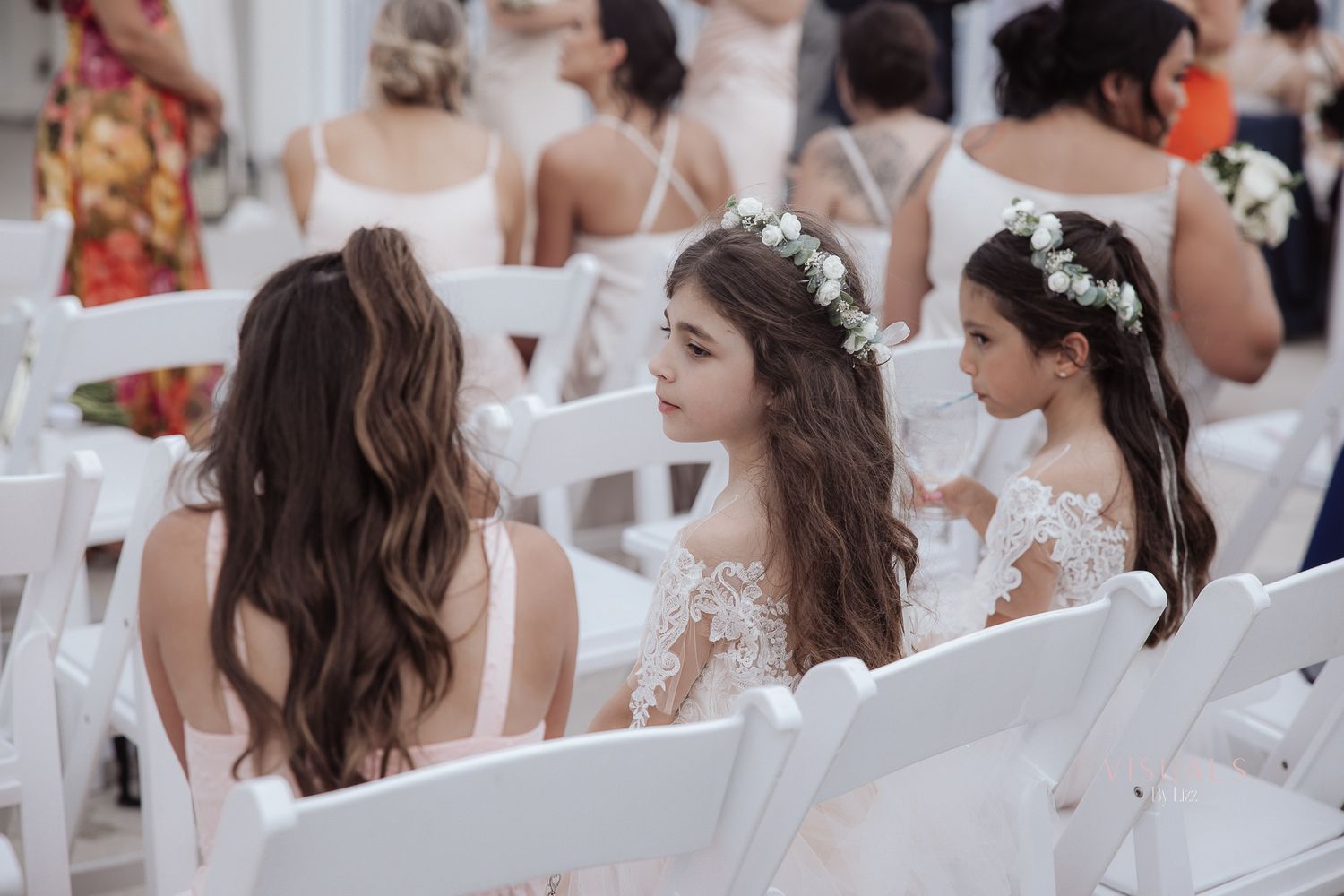 A group of bridesmaids in white dresses gather together for an elegant wedding celebration.