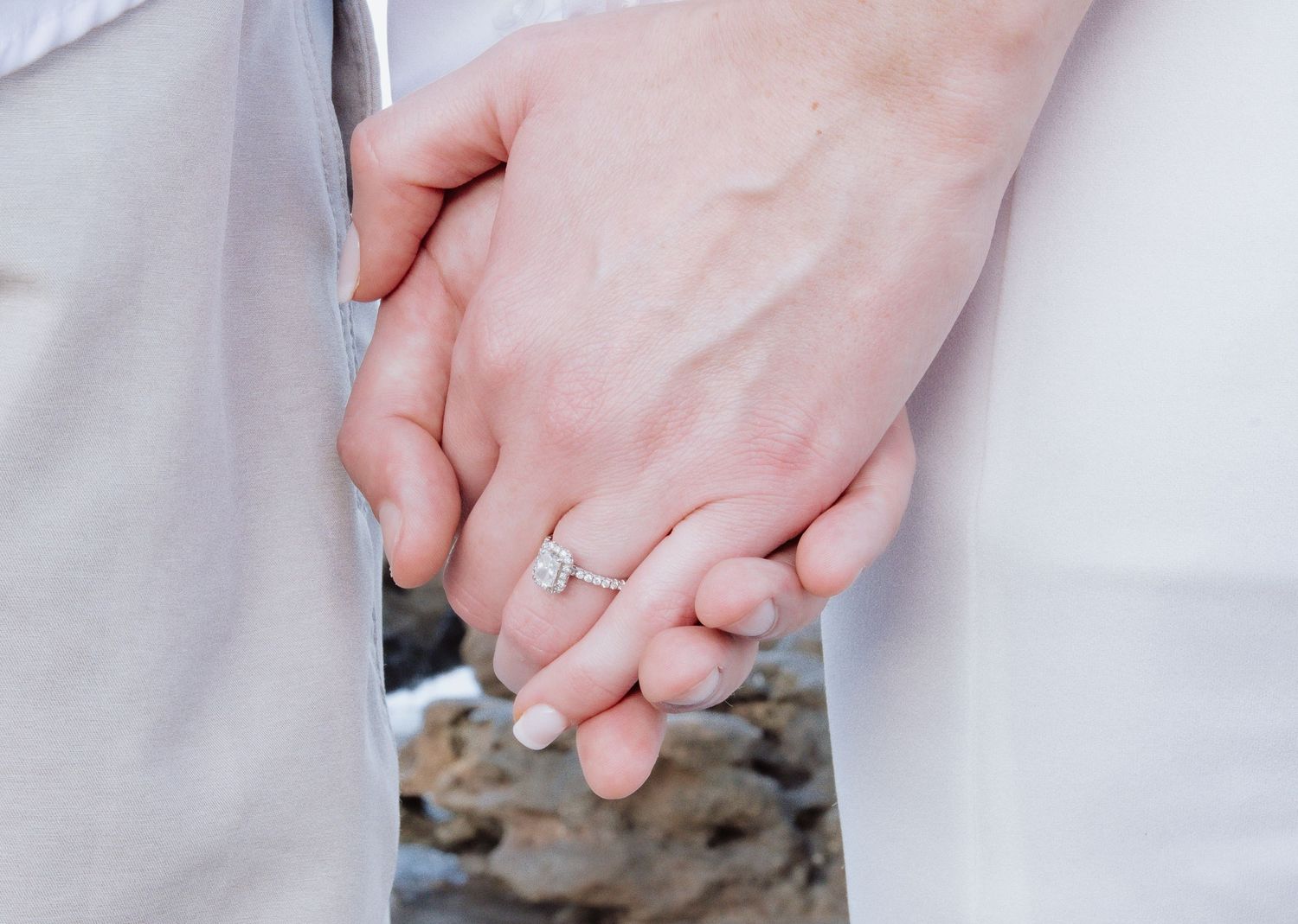 Close-up shots of hands displaying a stunning engagement ring against a white background.