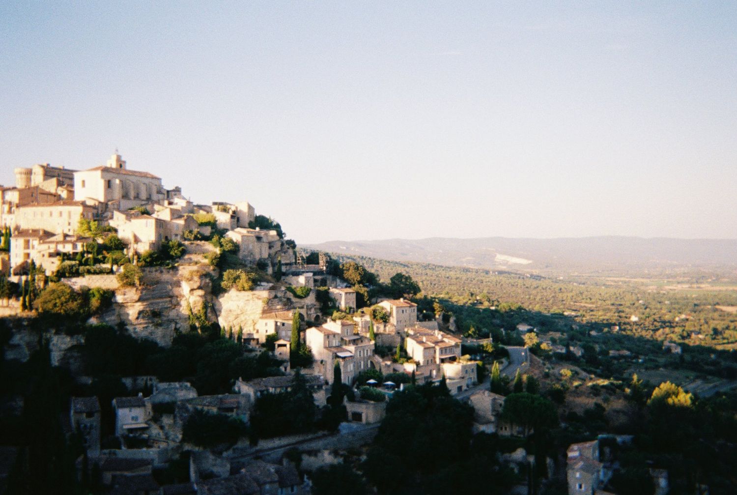 Hilltop village of Gordes in Provence, France, with stone buildings cascading down the slope at golden hour. Shannon Greene Photography