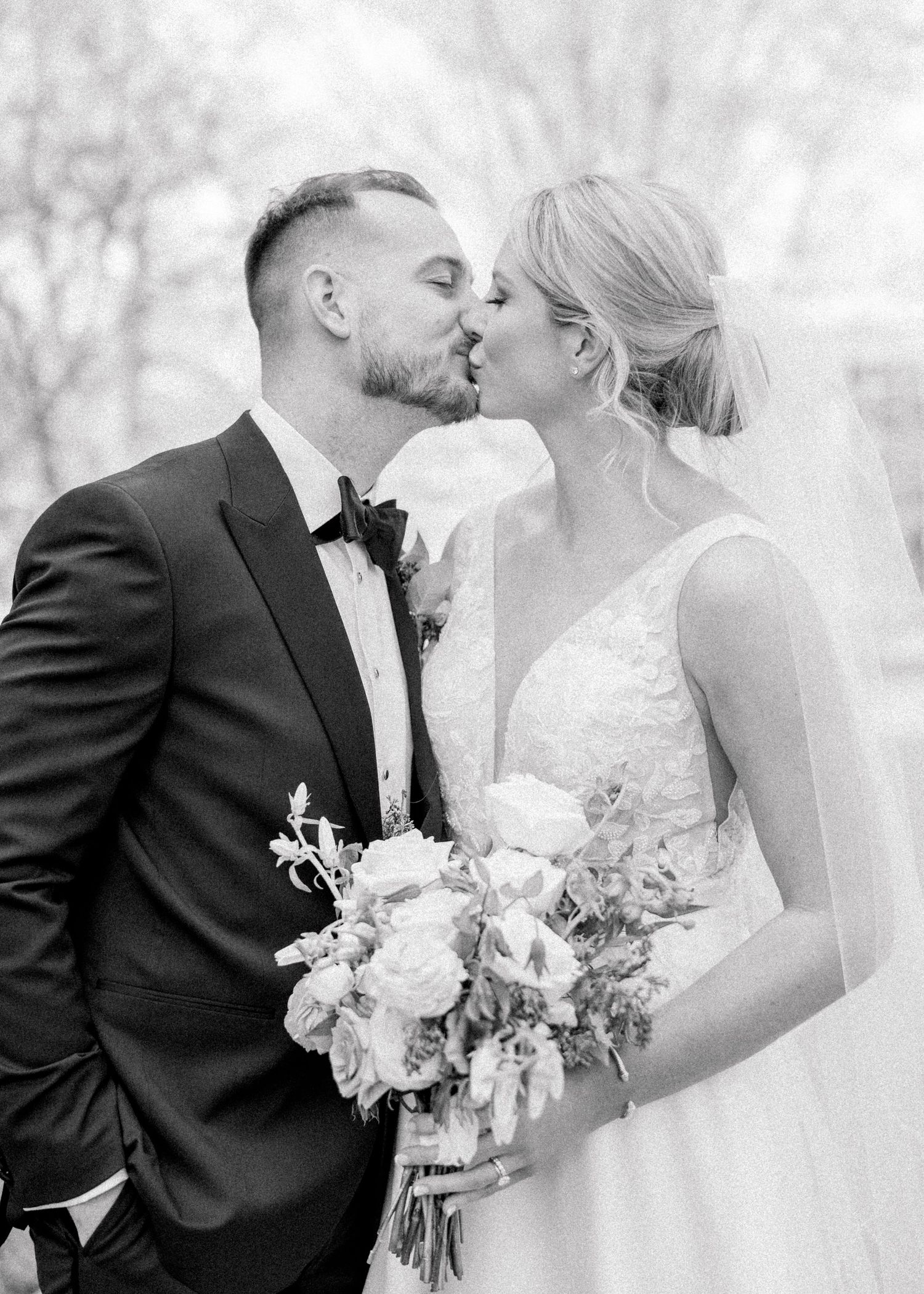 Black and white photo of a bride and groom sharing a kiss, bride holding a bouquet on their wedding day. NJ Wedding Photographer