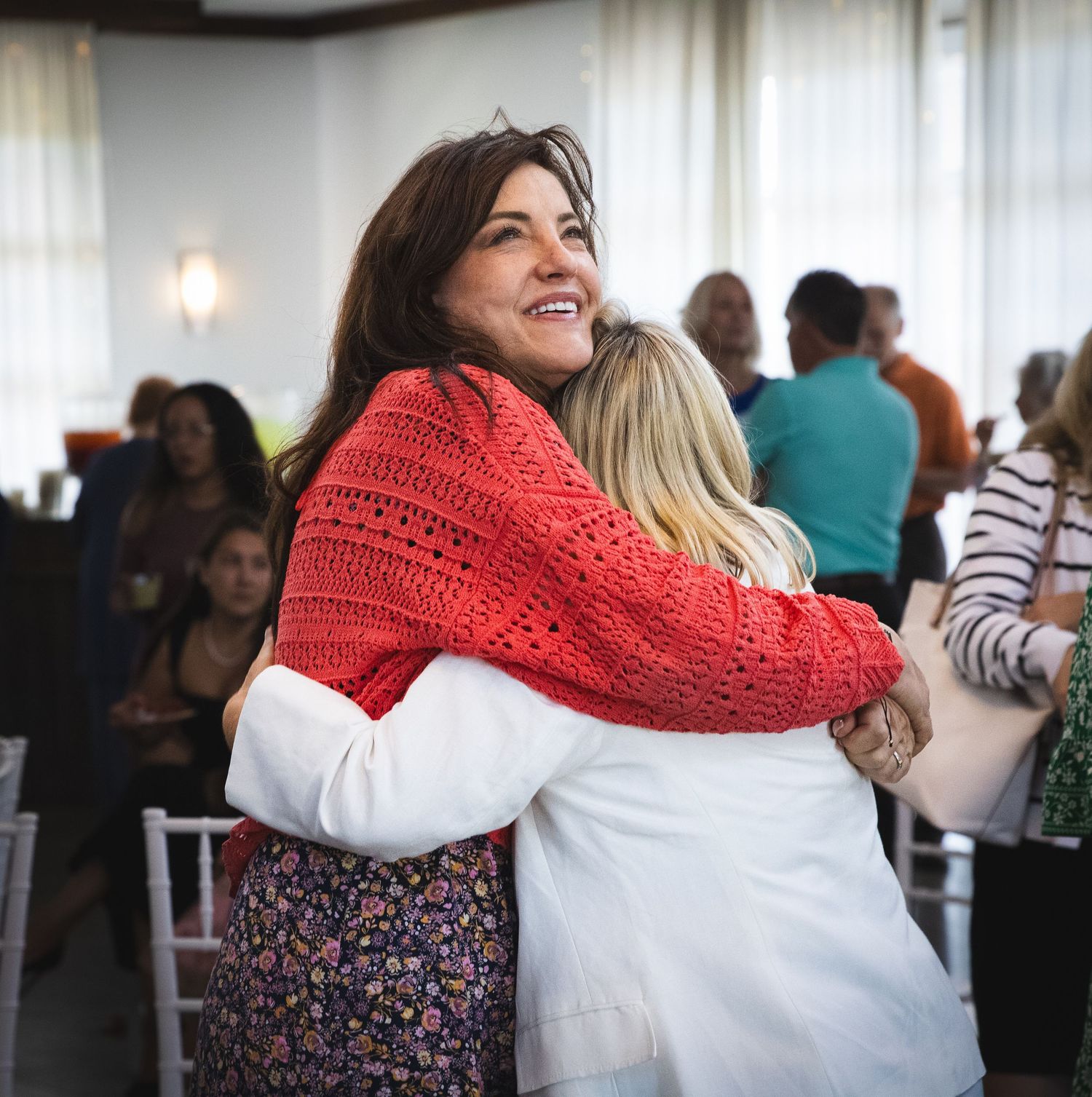 Two women share a warm hug at a bright celebration of life event in Charlotte NC