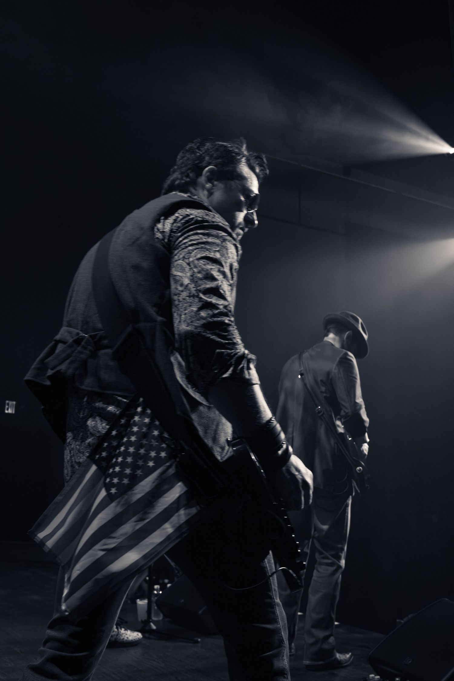 Black and white photo of rock musicians performing on a dramatic fog-lit stage in Charlotte, NC.