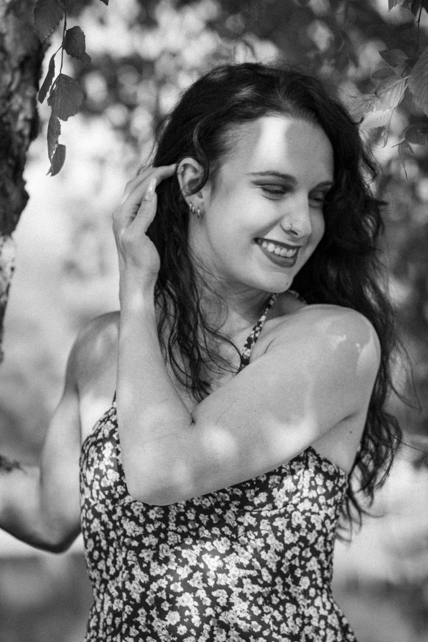 Black and white portrait of smiling brunette woman standing under tree branches at McAlpine Park in Charlotte NC