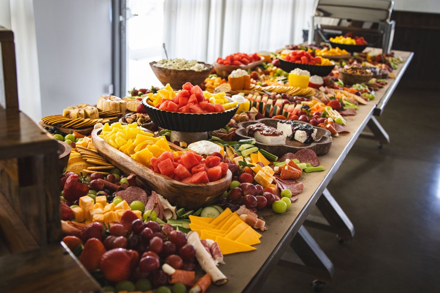 Abundant party grazing table filled with colorful fruits, cheeses, crackers, and charcuterie at celebration of life event.