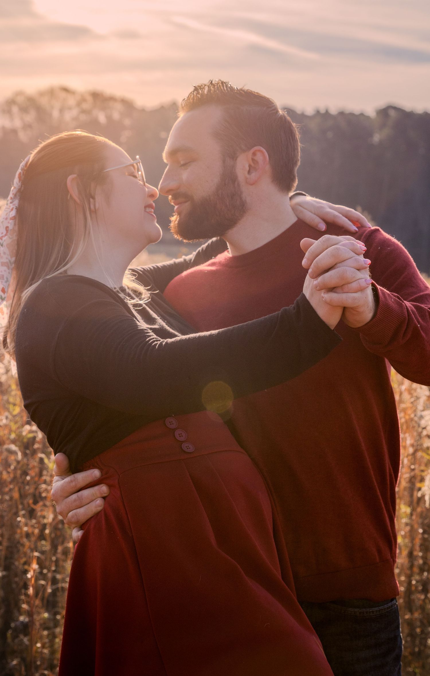 Romantic couple slow dancing in a sunlit field, smiling and gazing at each other during golden hour In Matthews, NC.