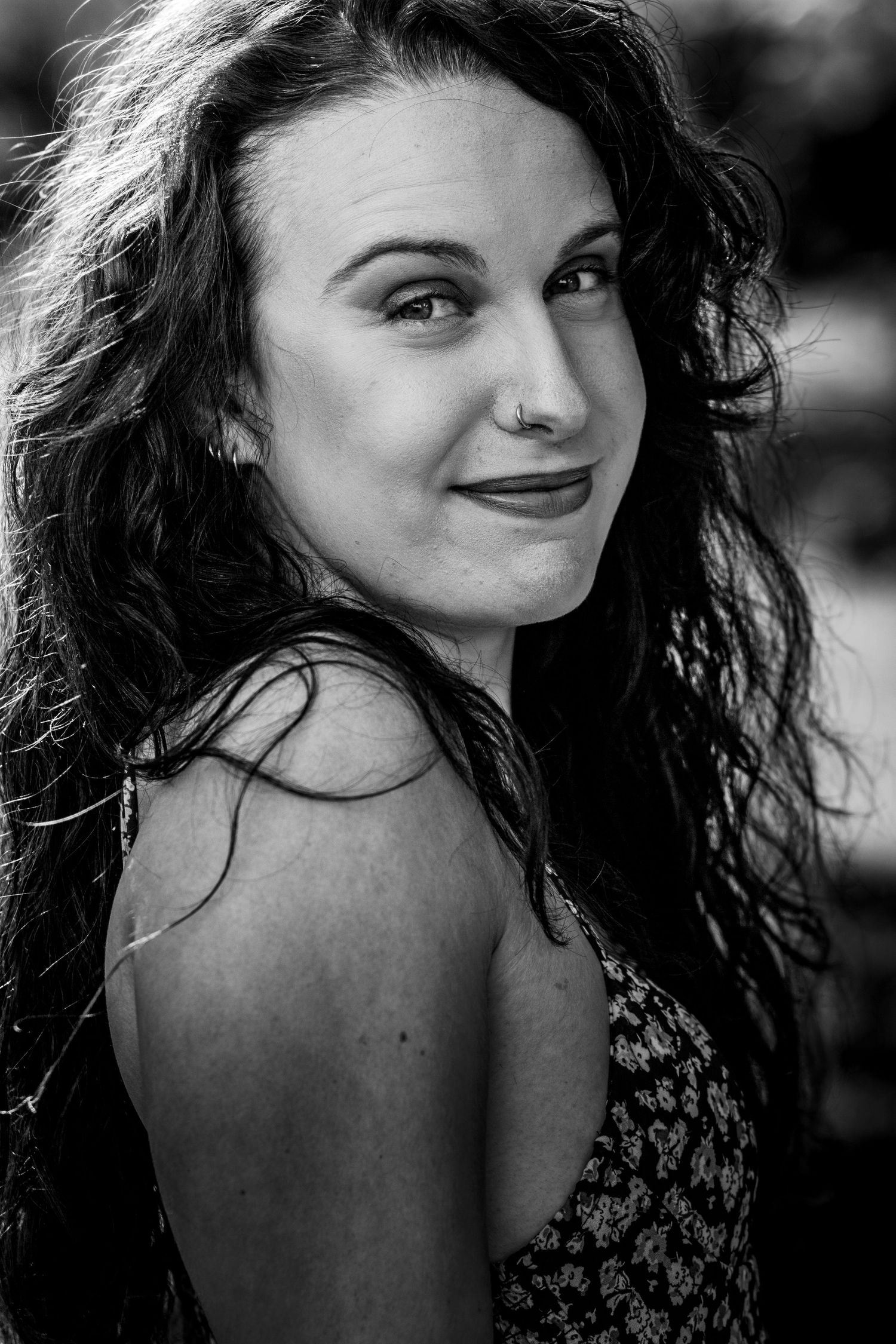 Black and white portrait senior/grad portrait of a young woman with long wavy hair and a nose ring.