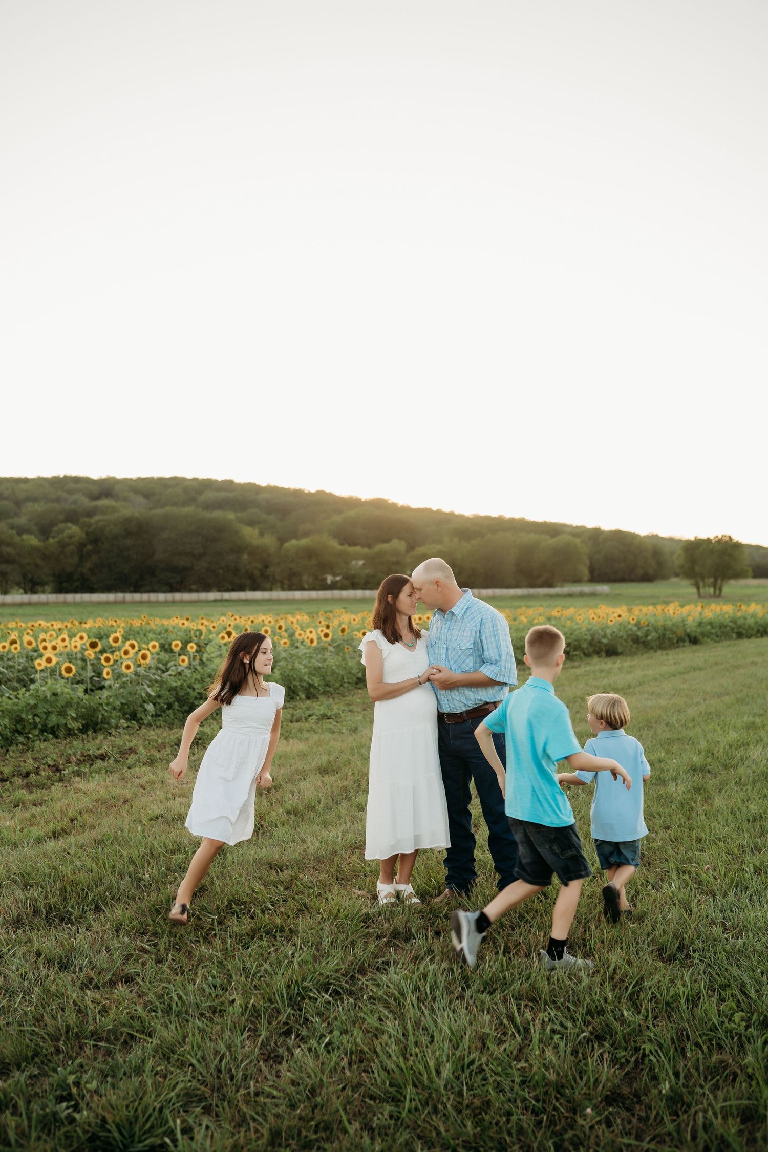 Family laughing together in sunflower field during Lawrence Kansas family photography session