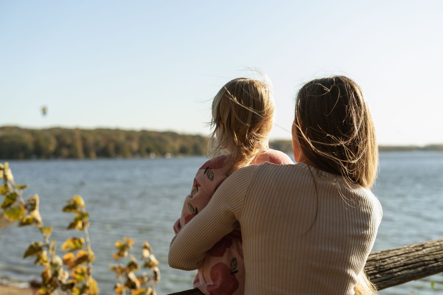 Two people sitting together overlooking a serene lake view with golden sunlight.