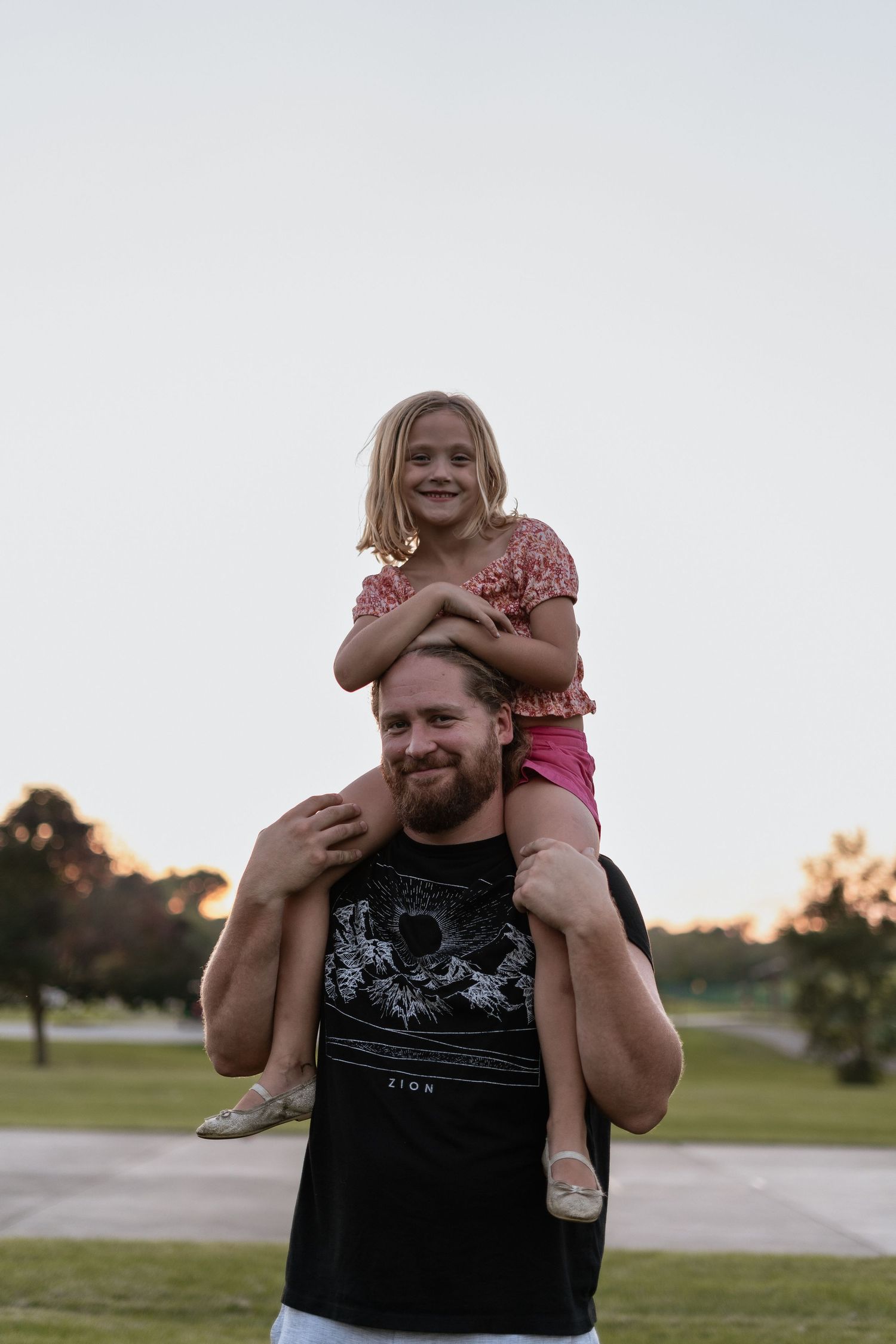 A joyful shoulder ride scene captured during a relaxed evening outdoors.