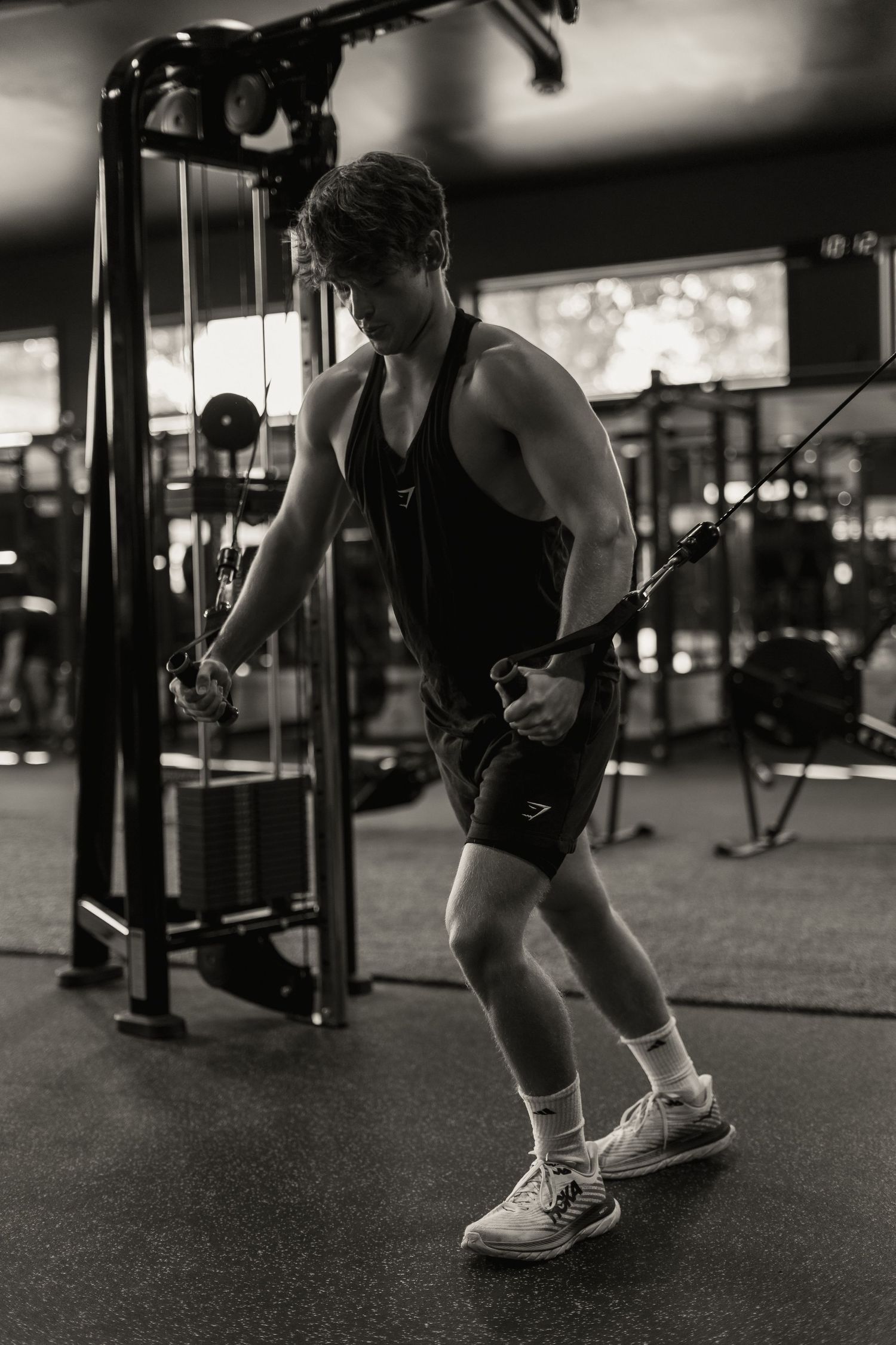 Person exercising with cable machine in black and white gym photo.