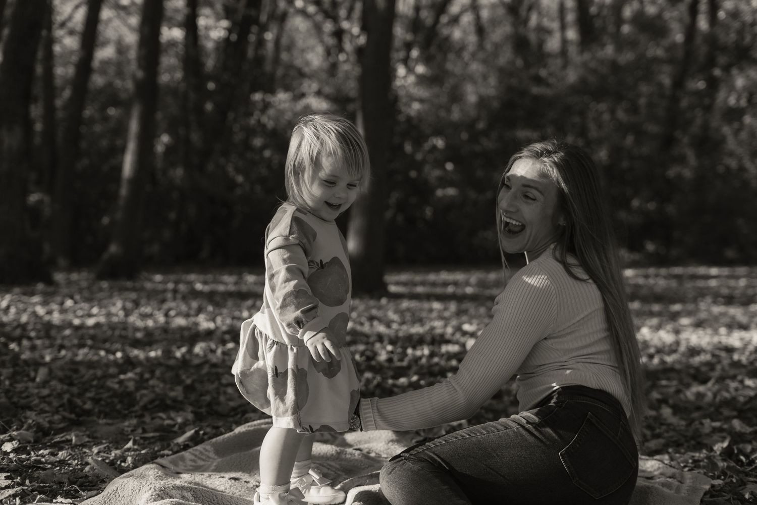 A loving interaction between parent and child sitting together outdoors in a wooded setting.