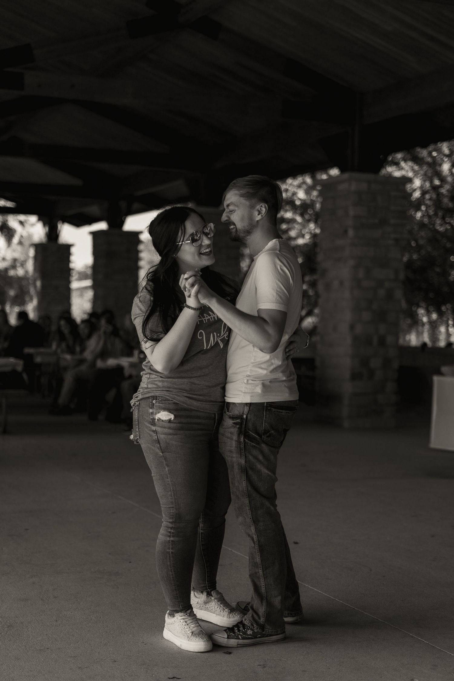 A romantic couple dancing together under a covered outdoor space in black and white photography.