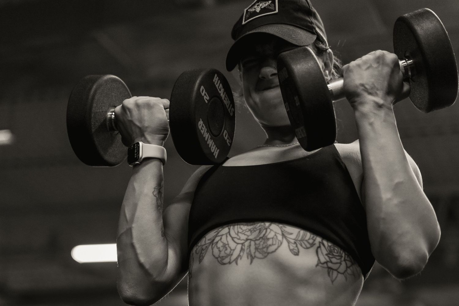 A person in workout attire lifting dumbbells during a strength training session.