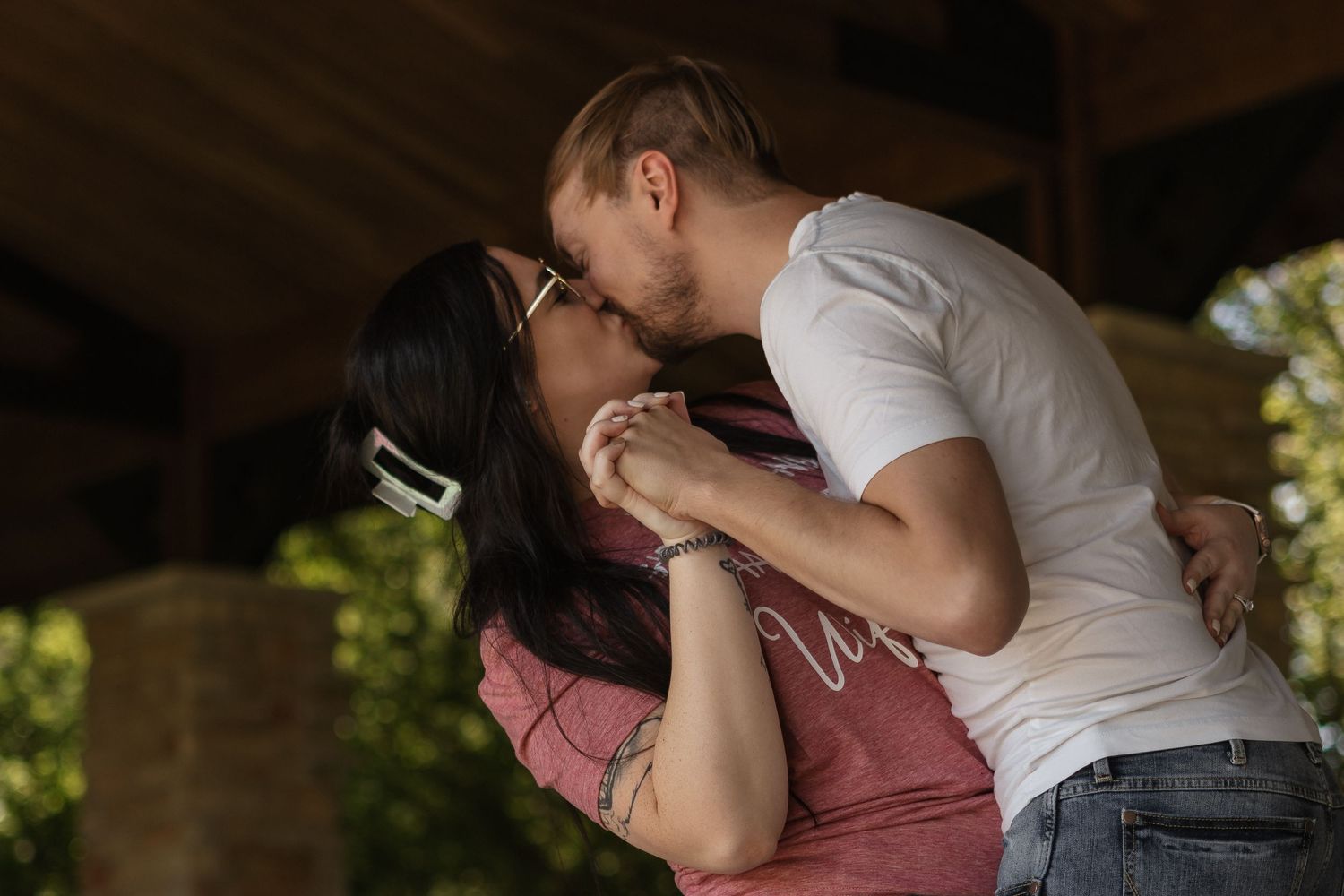 A tender moment between a couple sharing an intimate embrace under a covered patio.