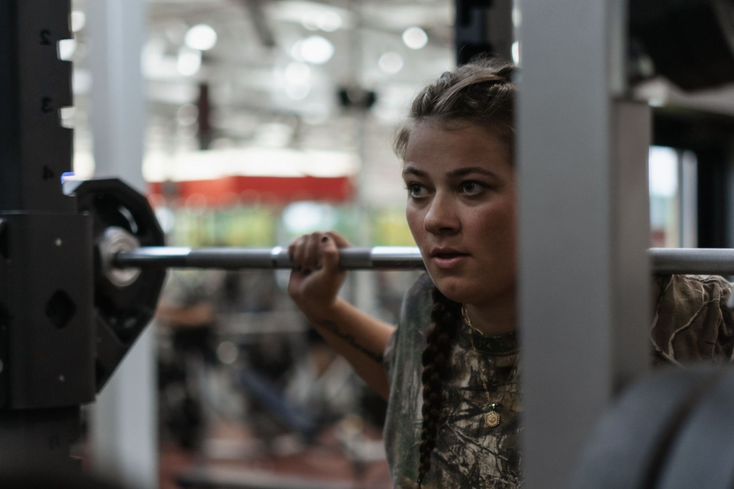 Person performing barbell exercise in dimly lit gym setting.