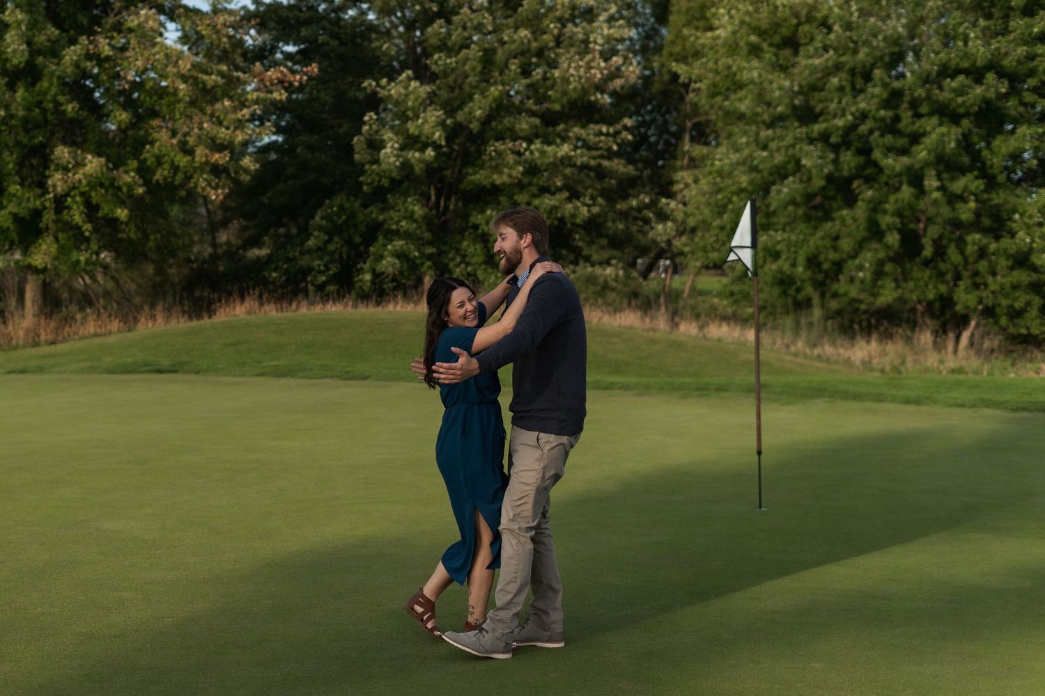 A couple practicing their golf putting together on a green course during a sunny day.
