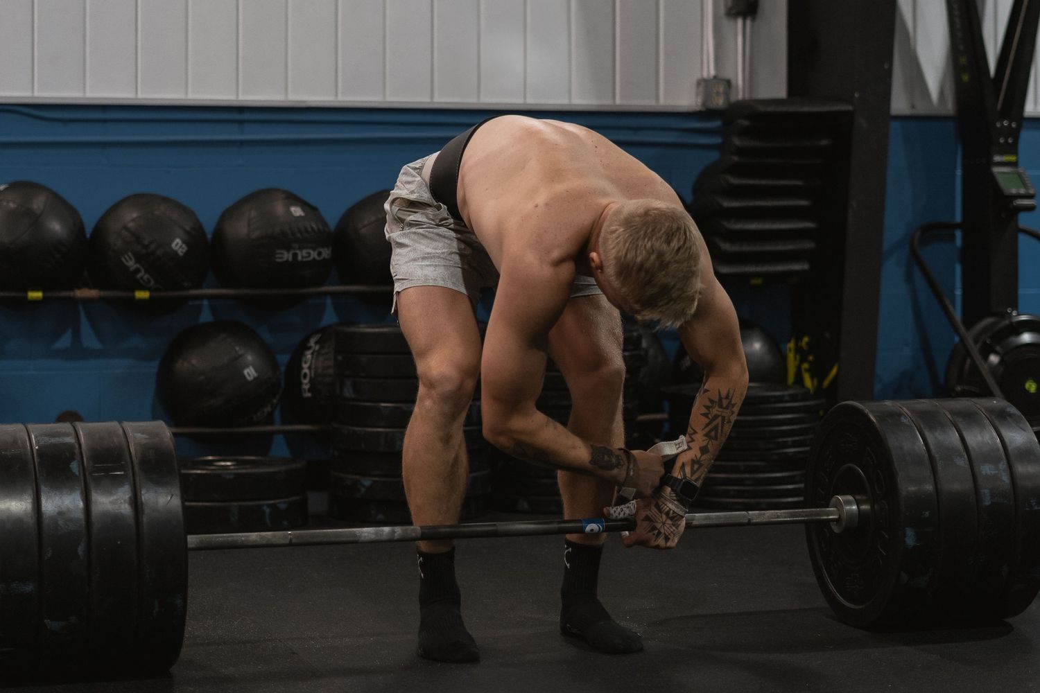 An athlete prepares to lift heavy weights in a dimly lit gym setting.