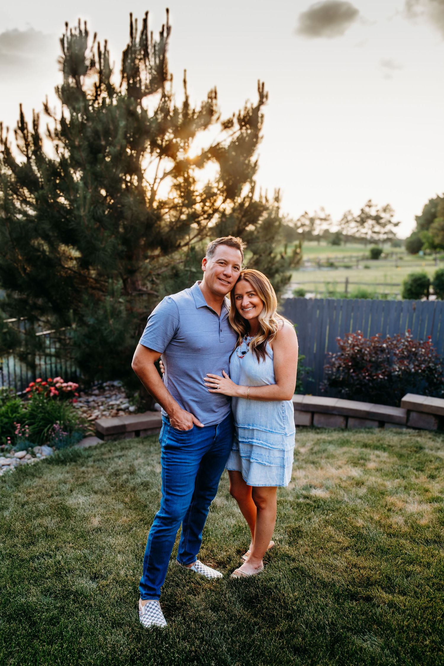 Man and woman standing together, smiling toward camera, in beautiful backyard in Centennial, Colorado.