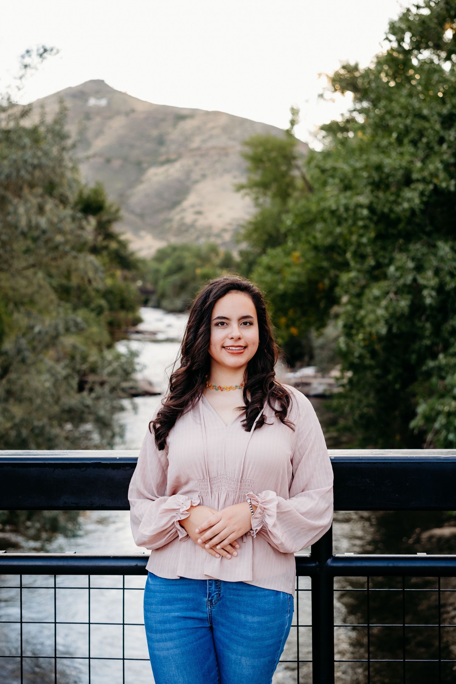 Senior portraits for teen girl standing against bridge over Clear Creek in downtown Golden for senior portraits.