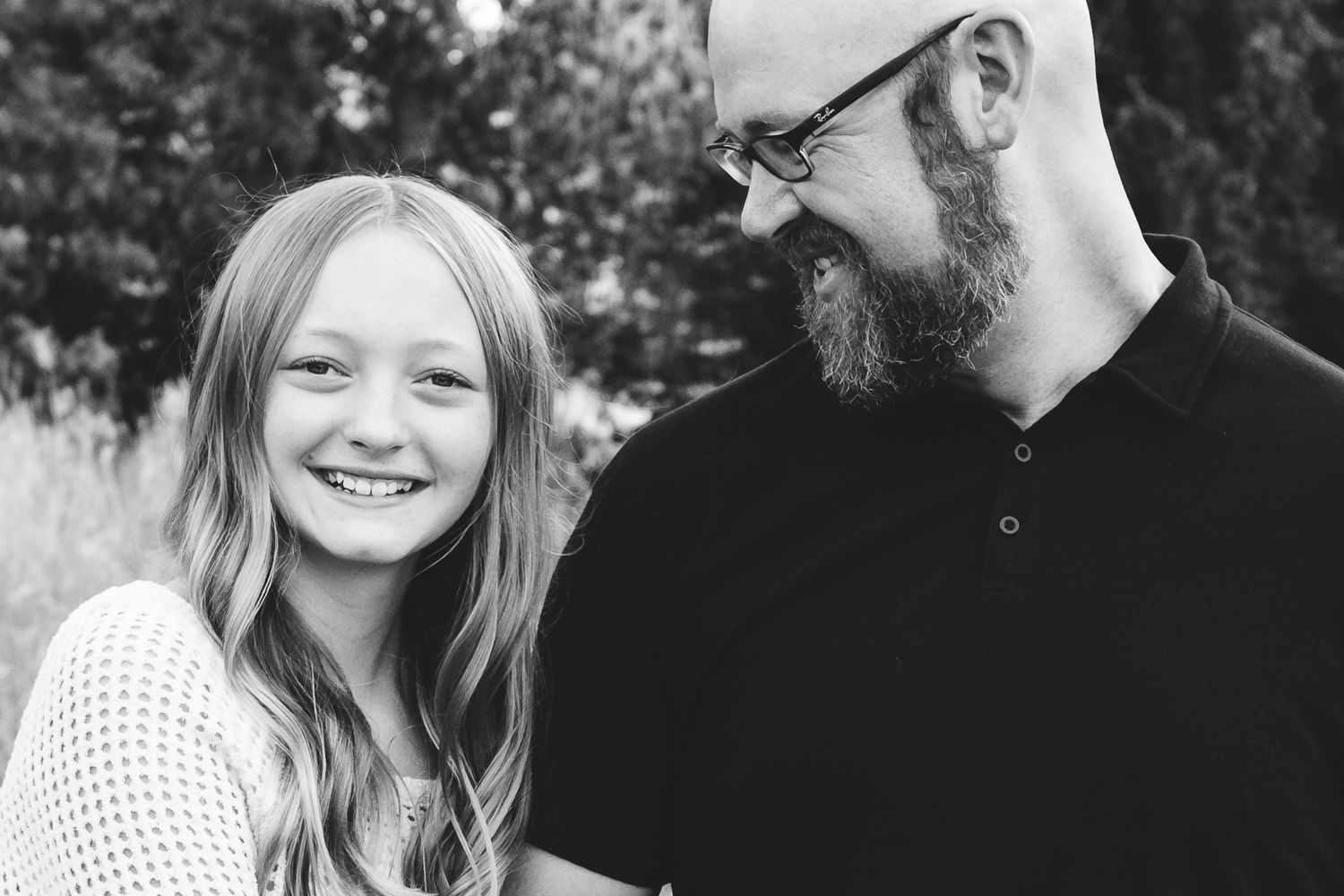 Black and white portrait of father and preteen daughter, father peering down at daughter.