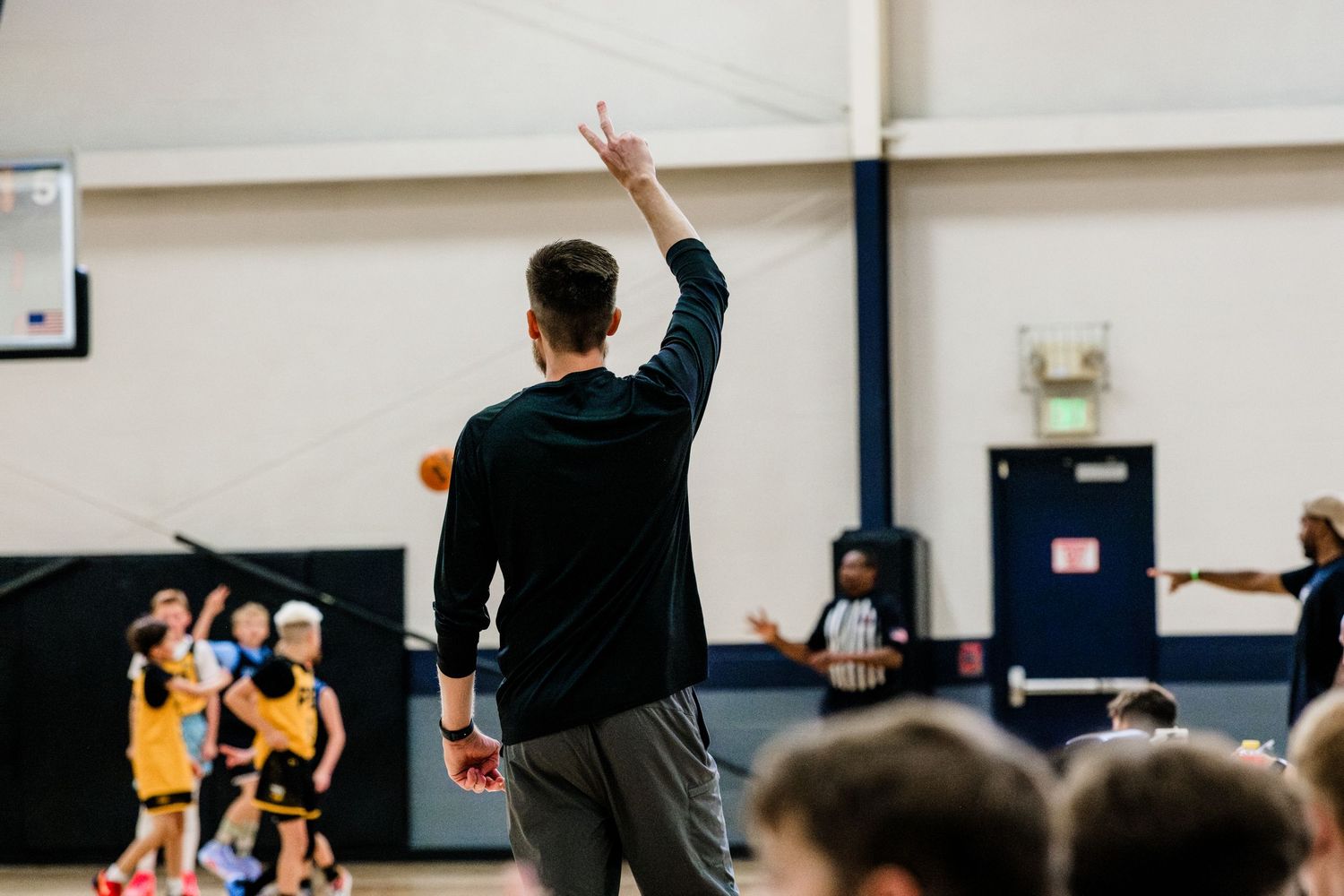 Basketball coach holding up the number two to signify a basketball play to players.