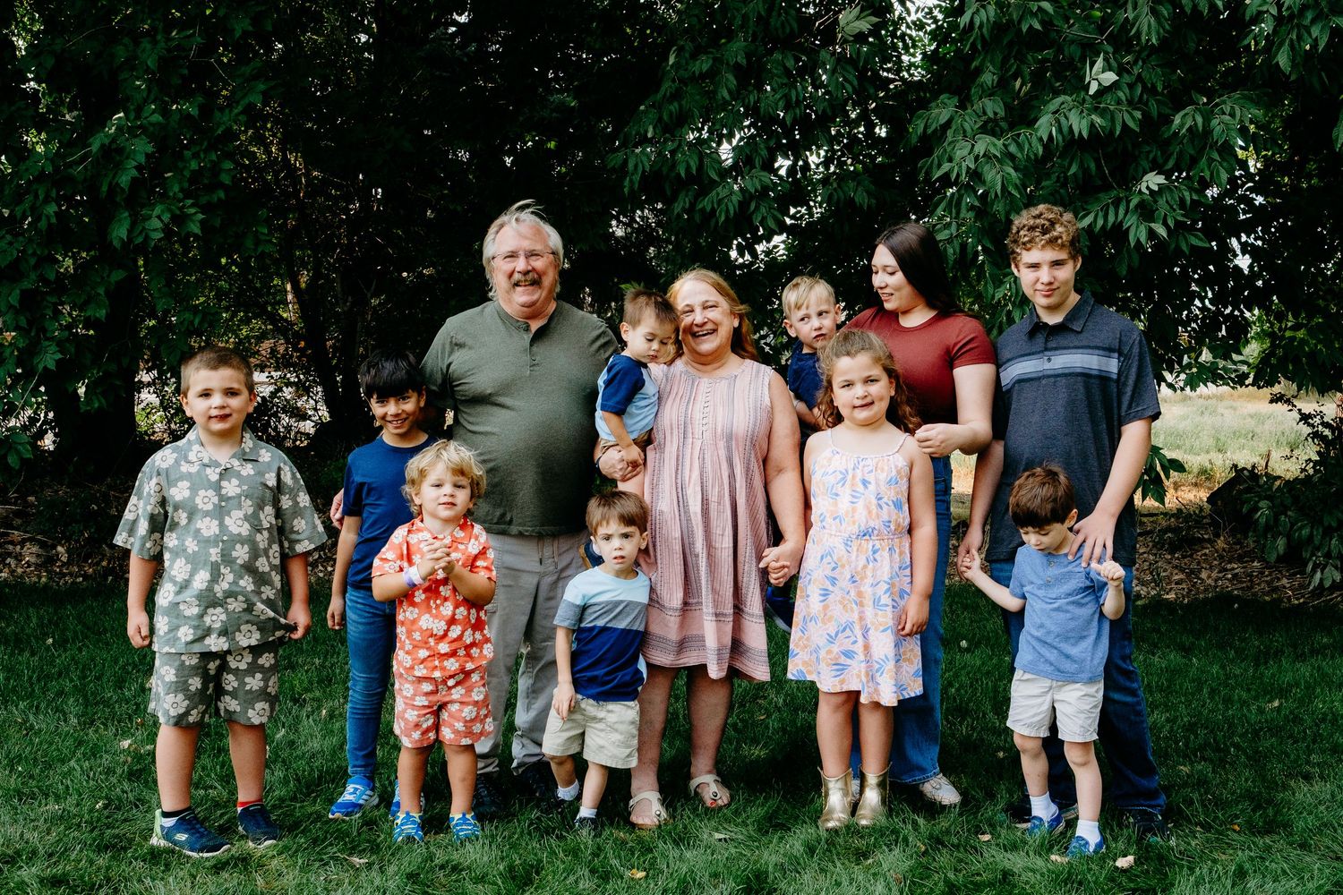 Grandparents standing with ten grandchildren, varying in ages from toddler to teenager in Golden, Colorado.