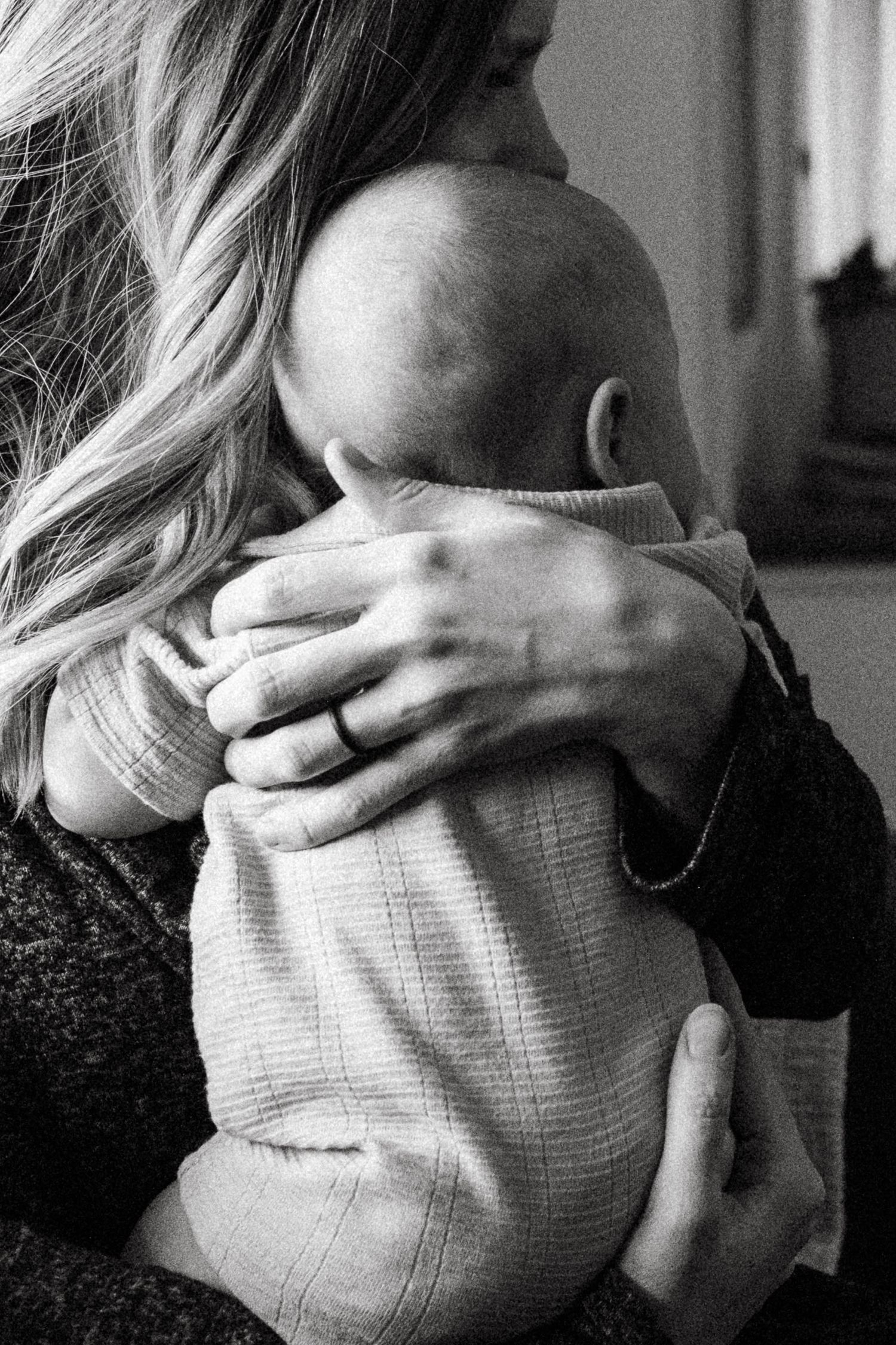 Black and white close up of mother's hands as she holds newborn.