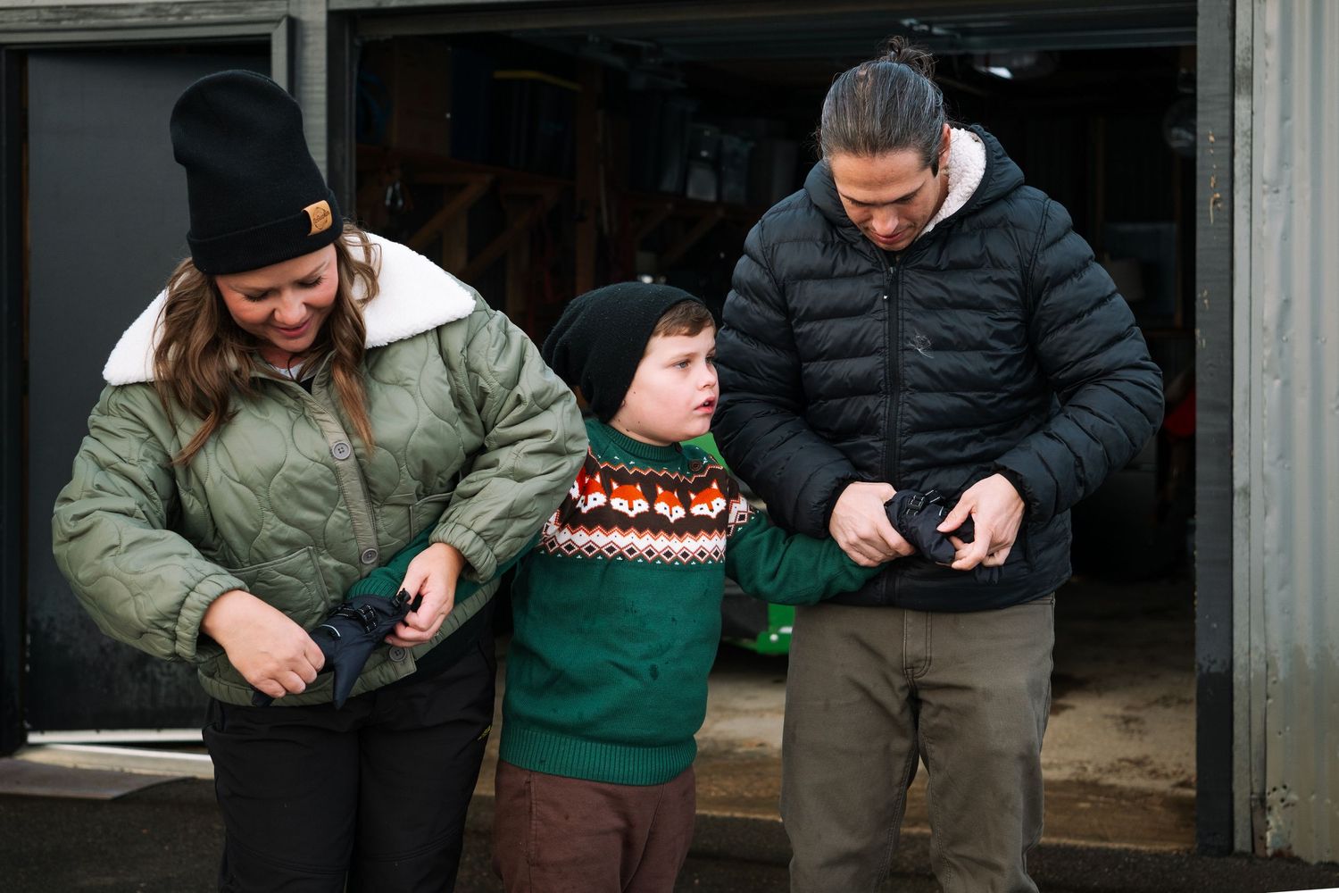 Mother and father putting gloves on son.