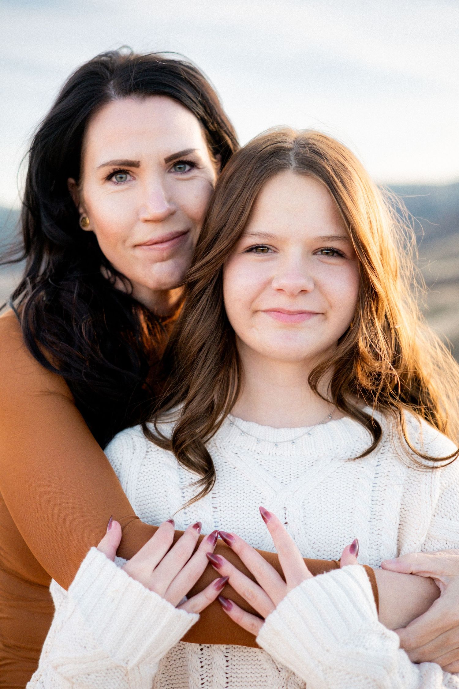 Mother peacefully embracing her teen daughter.