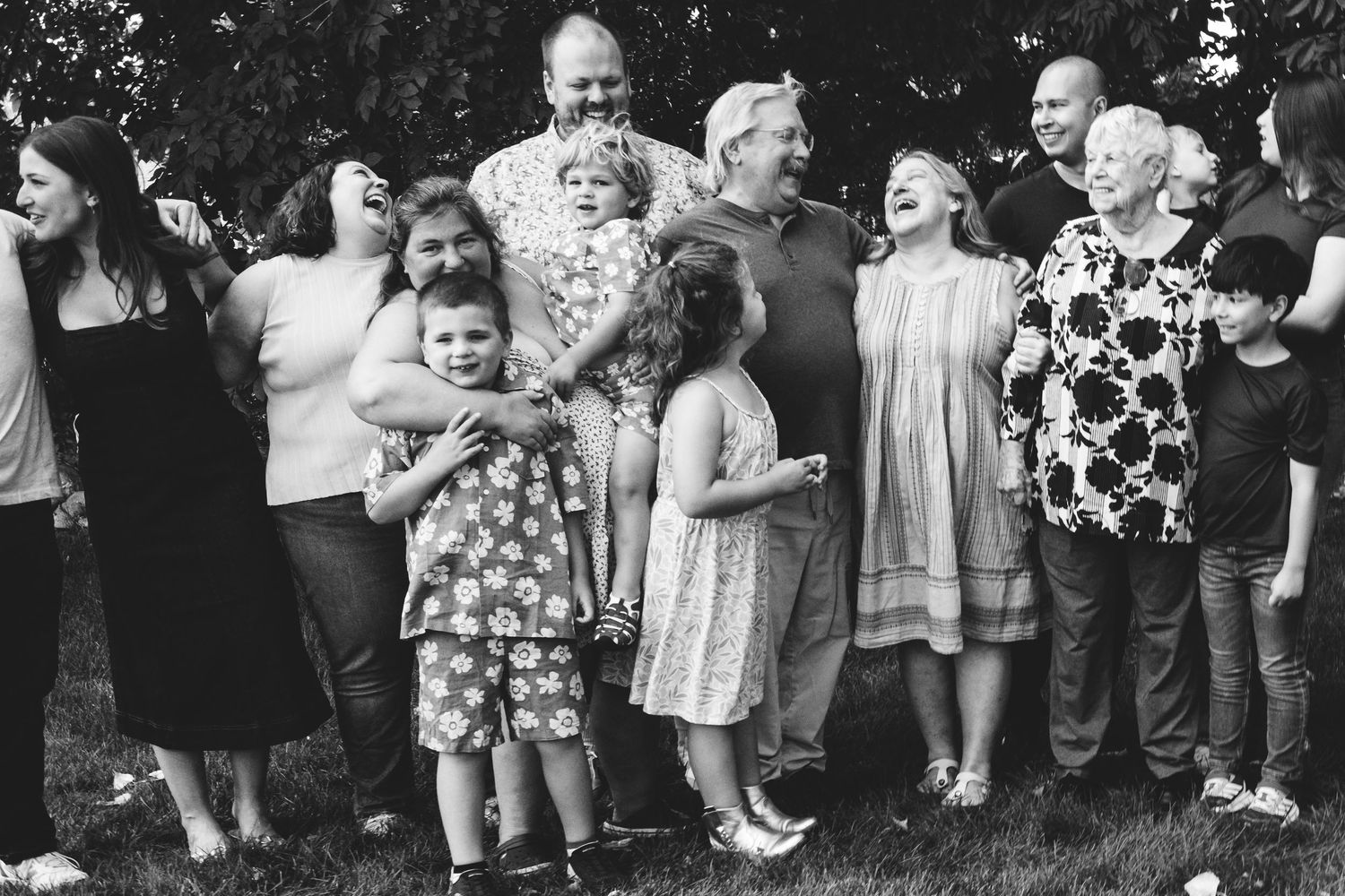 Candid family moment of four generations of family laughing, black and white.
