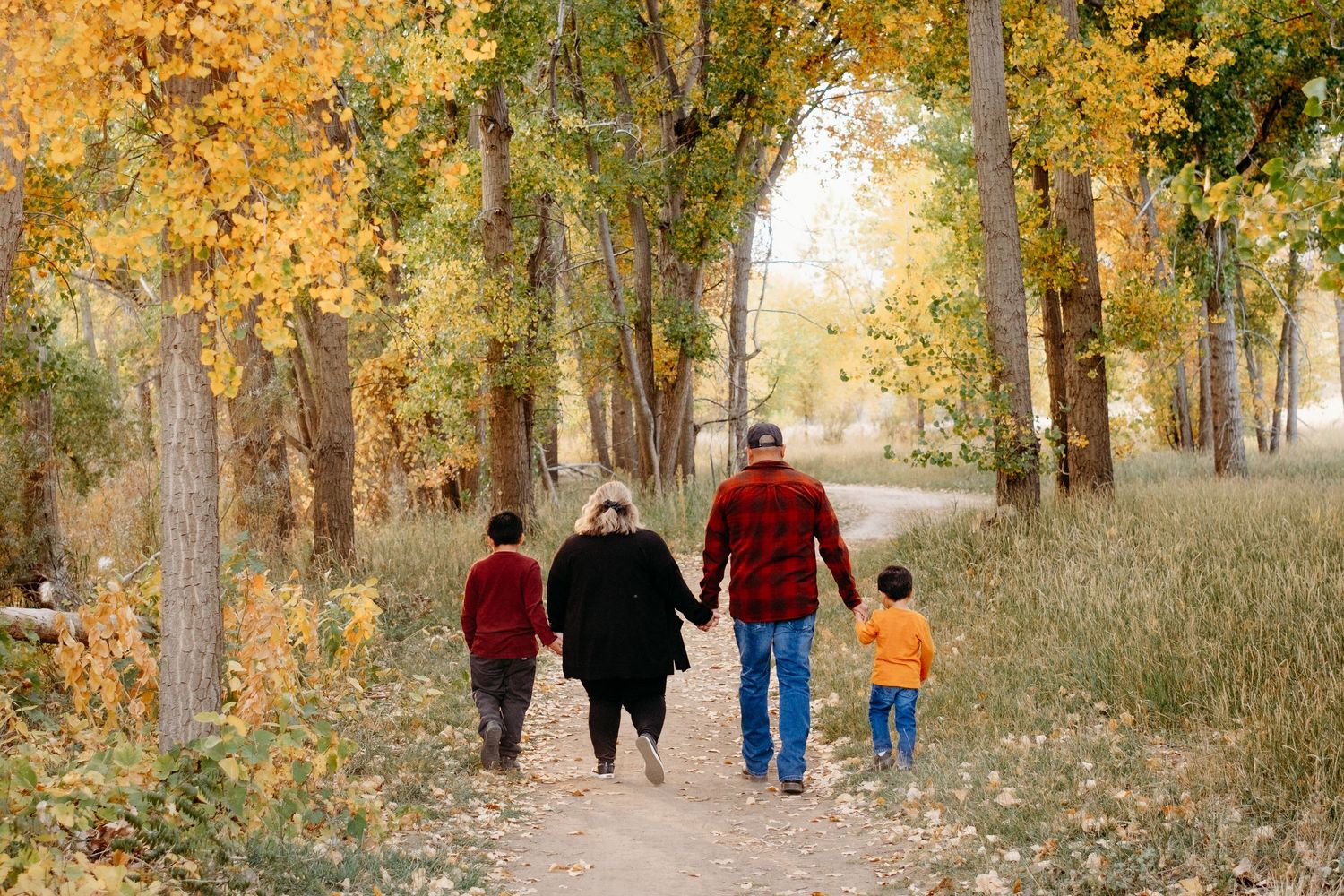 Family of four walking on a path through fall foresty area in Ber Creek Lake.