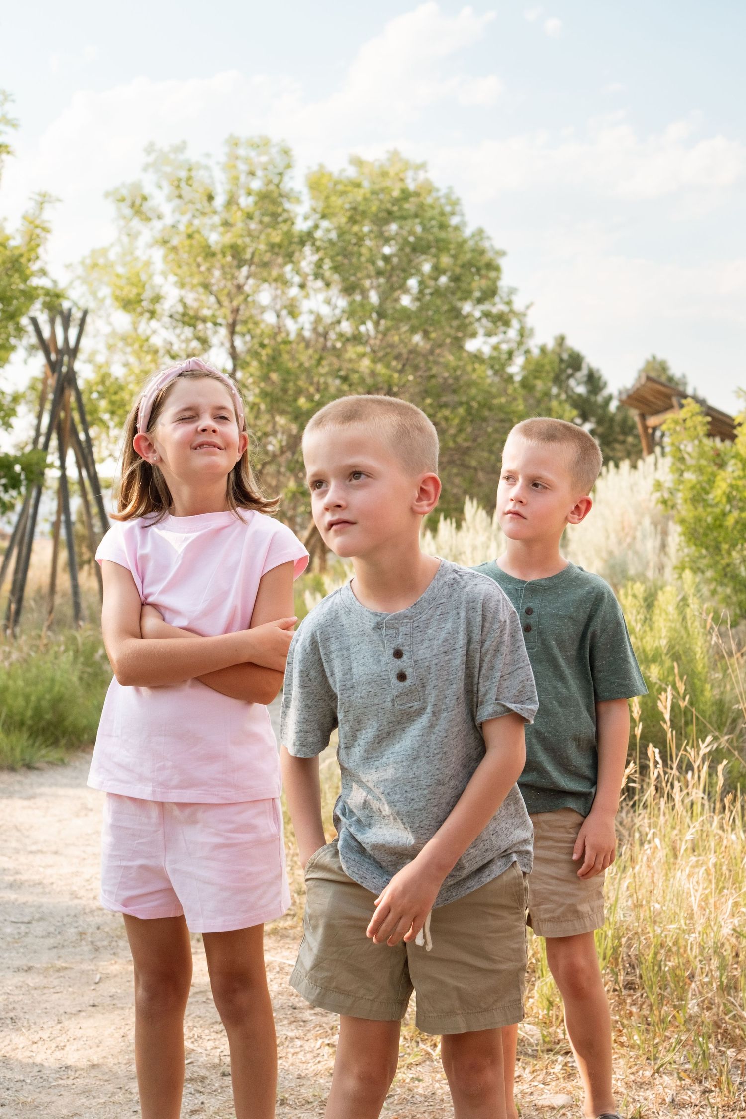 Portrait of sister and twin brothers on a summer day at a Denver park.