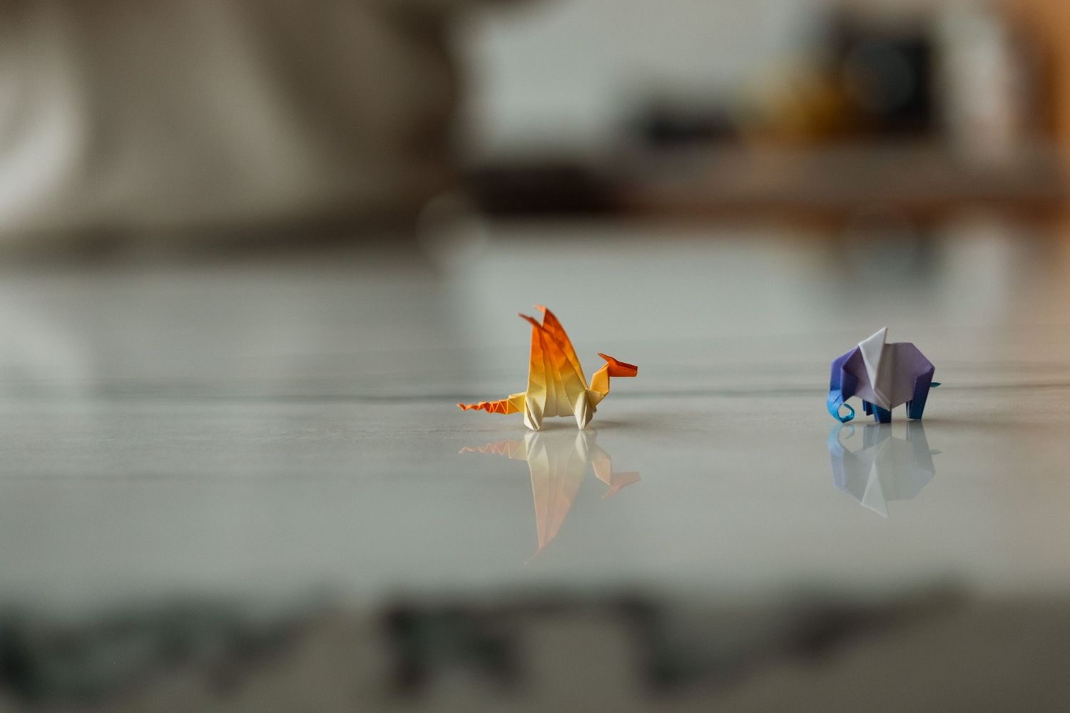 Tiny origami dragon and elephant on kitchen counter.