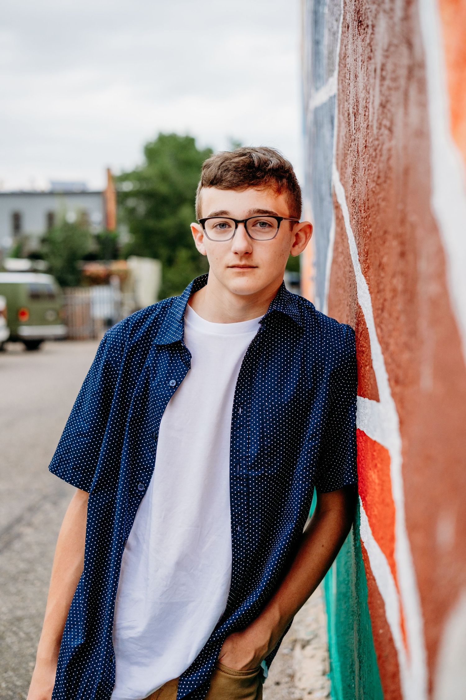 Teen portrait, leaning against colorful wall.