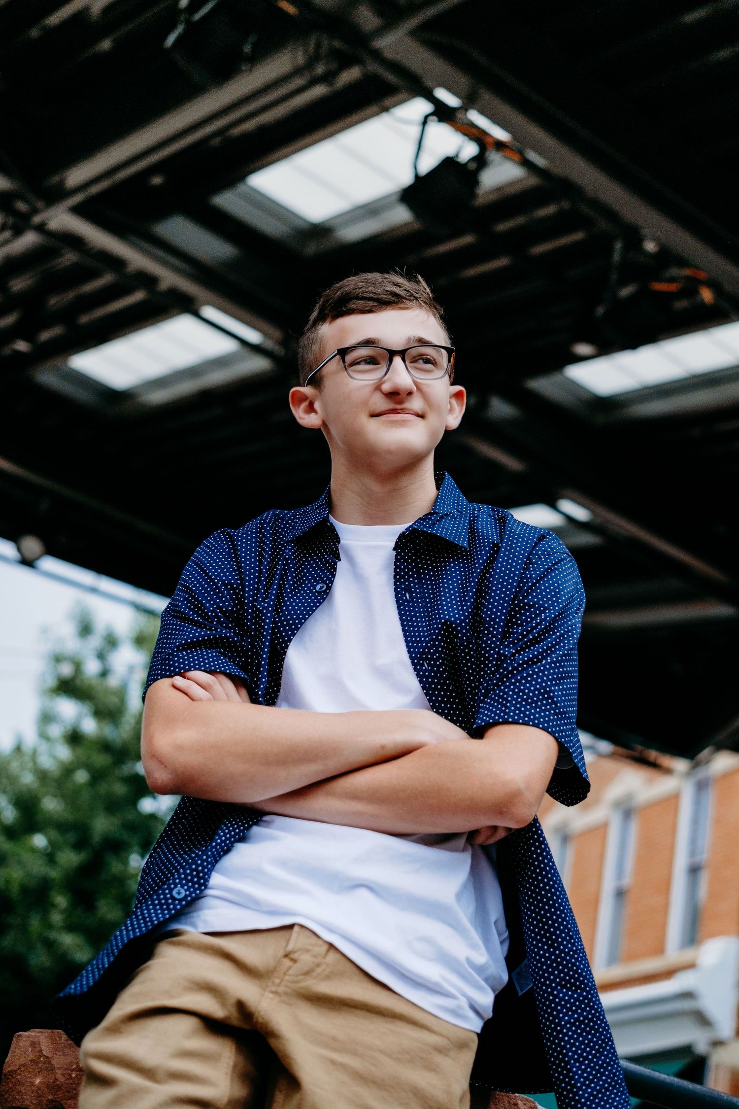 Senior portrait of a teenage boy in downtown Fort Collins, sitting at amphitheatre. Captured by a Denver senior photographer,