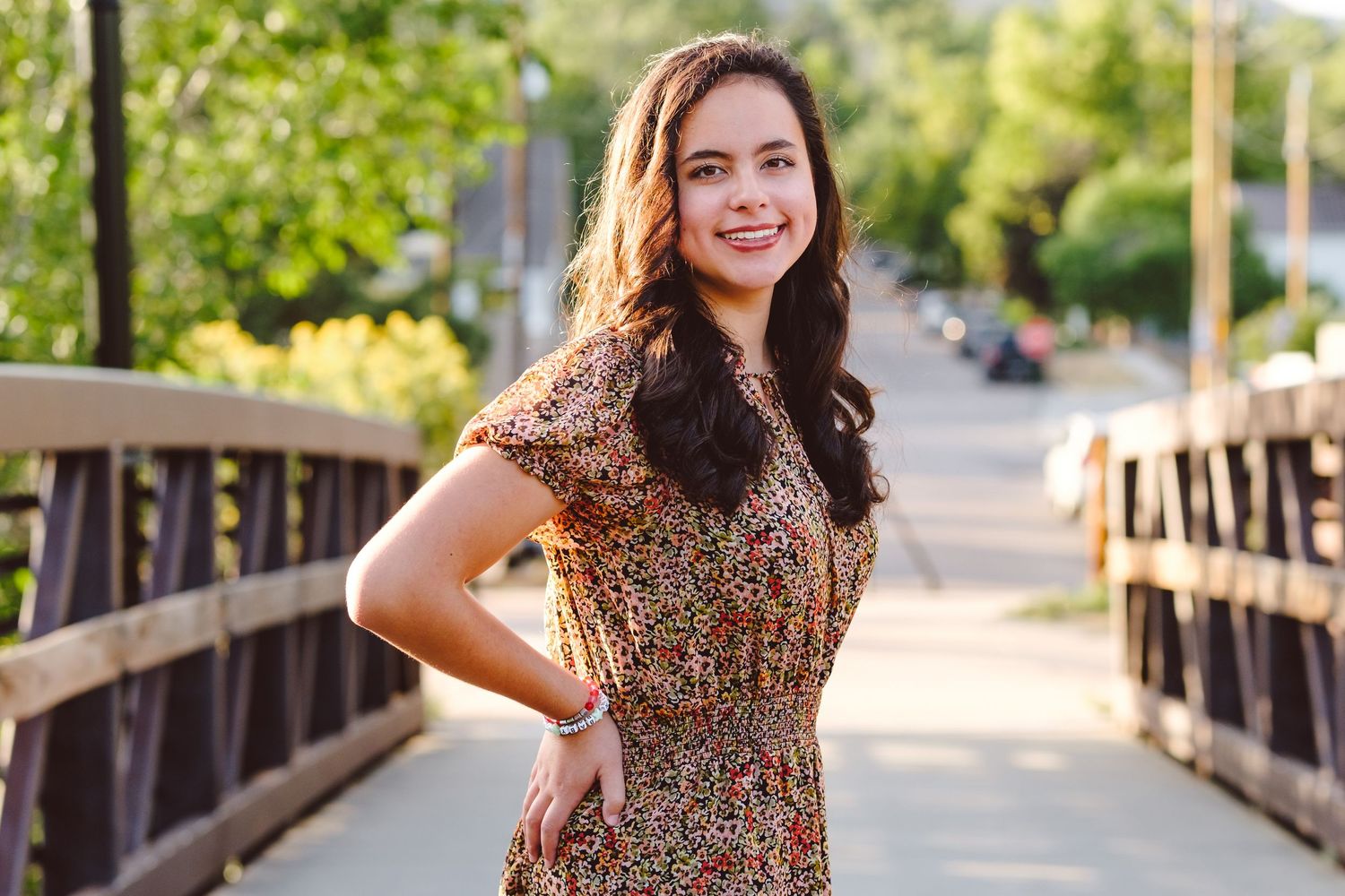 Teen girl standing on bridge in Golden, Colorado near Clear Creek for senior portraits.