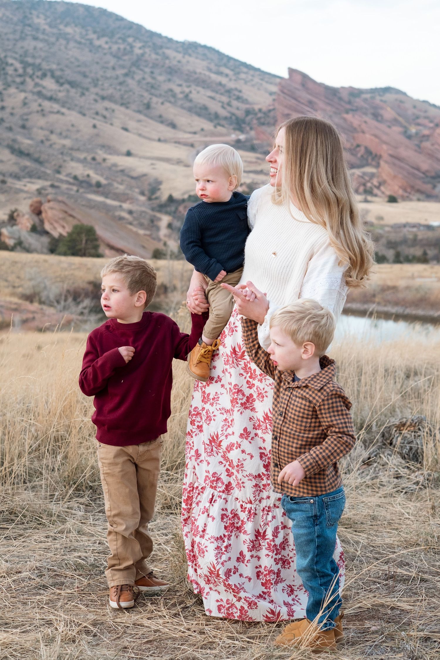 Mother with three young sons, all looking off into the distance, with Red Rocks views in the background.