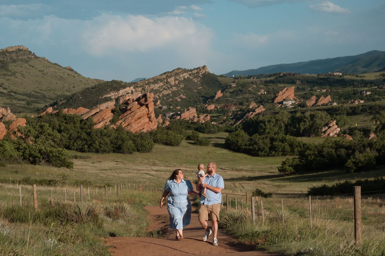 Mother and father walking on trailhead at South Valley Park, father holding son, stunning red rocks formations in the background.