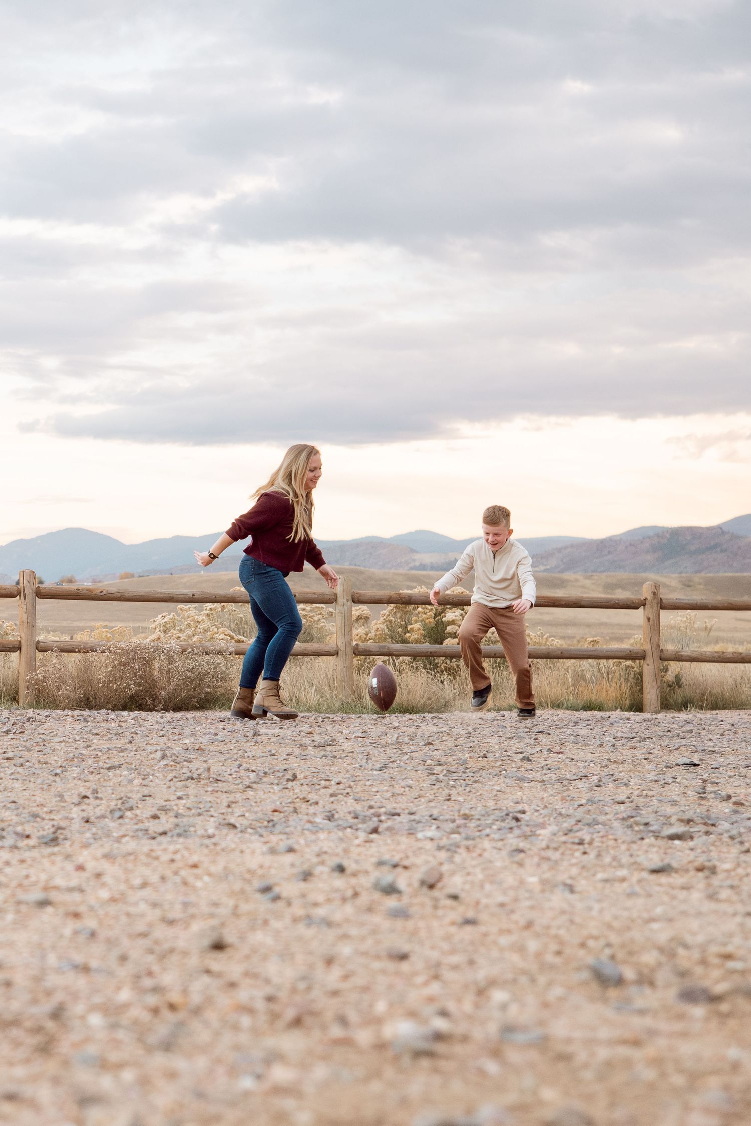 Mother chasing a football with son, mountains in the background.