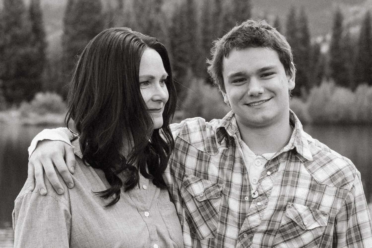 Black and white of mother gazing at teen son in Colorado mountains.