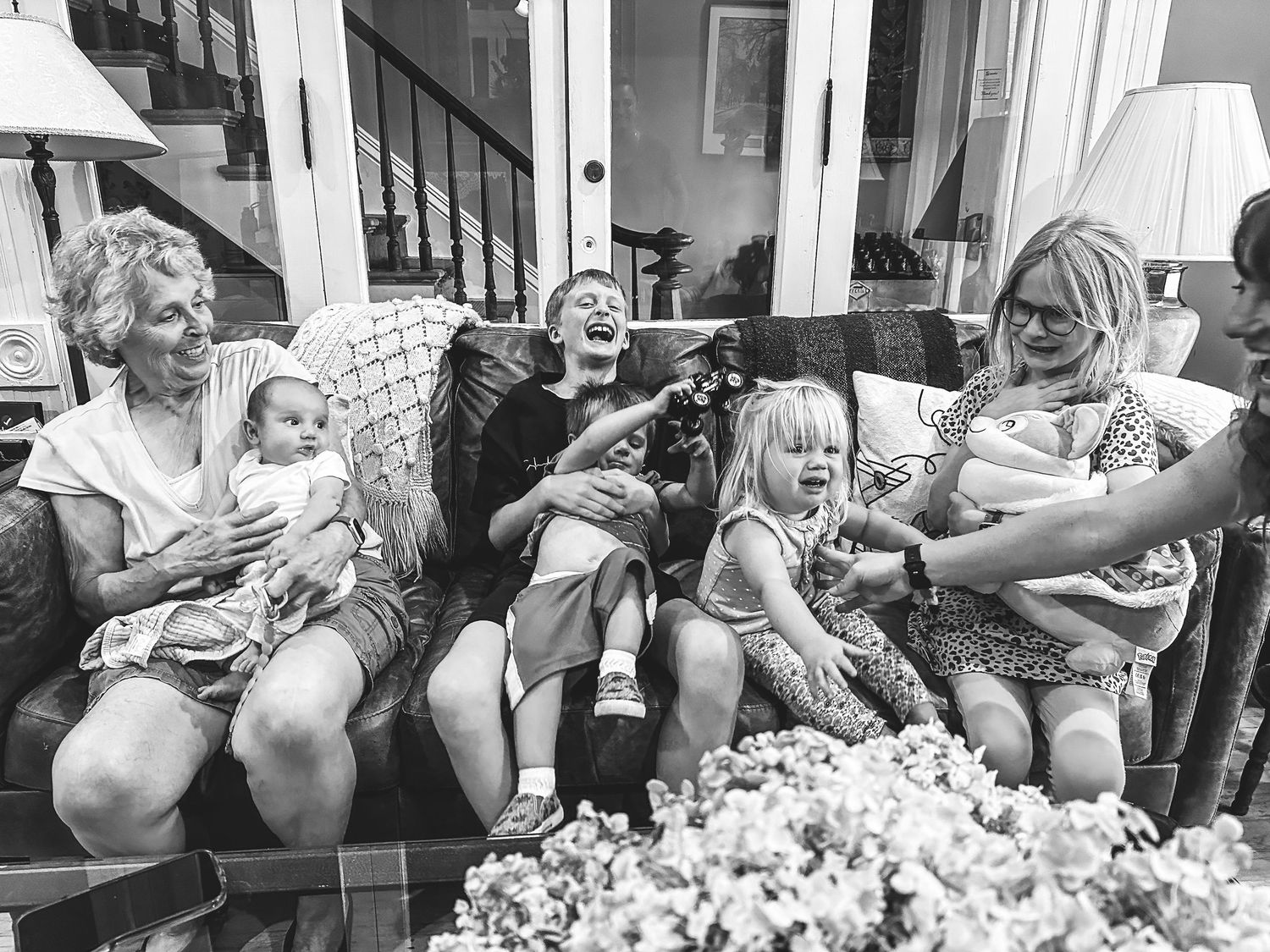Black and white portrait of great grandmother sitting with several grandchildren of various ages.