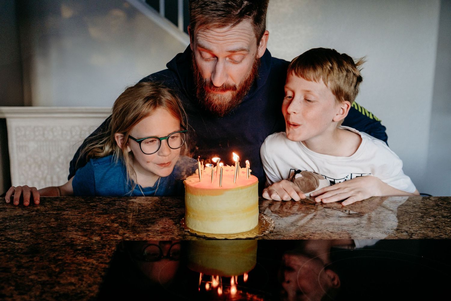 Denver photographer's project 365, May, father surrounded by two children at kitchen counter, blowing out candles.