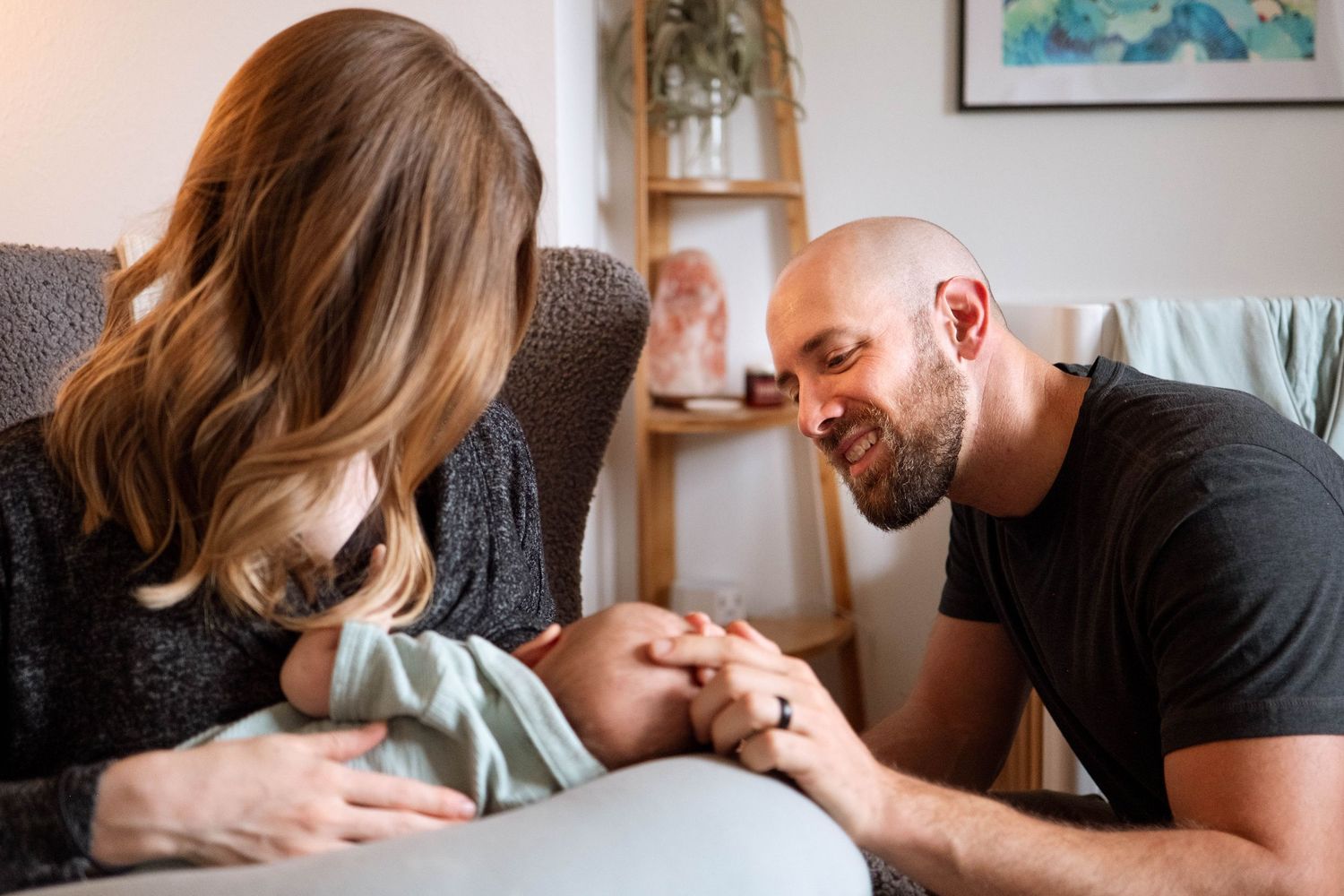 Mother feeding newborn, father caressing newborn's head.