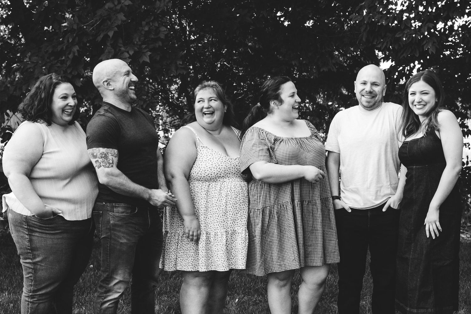 Black and white portrait of adult siblings laughing and smiling.