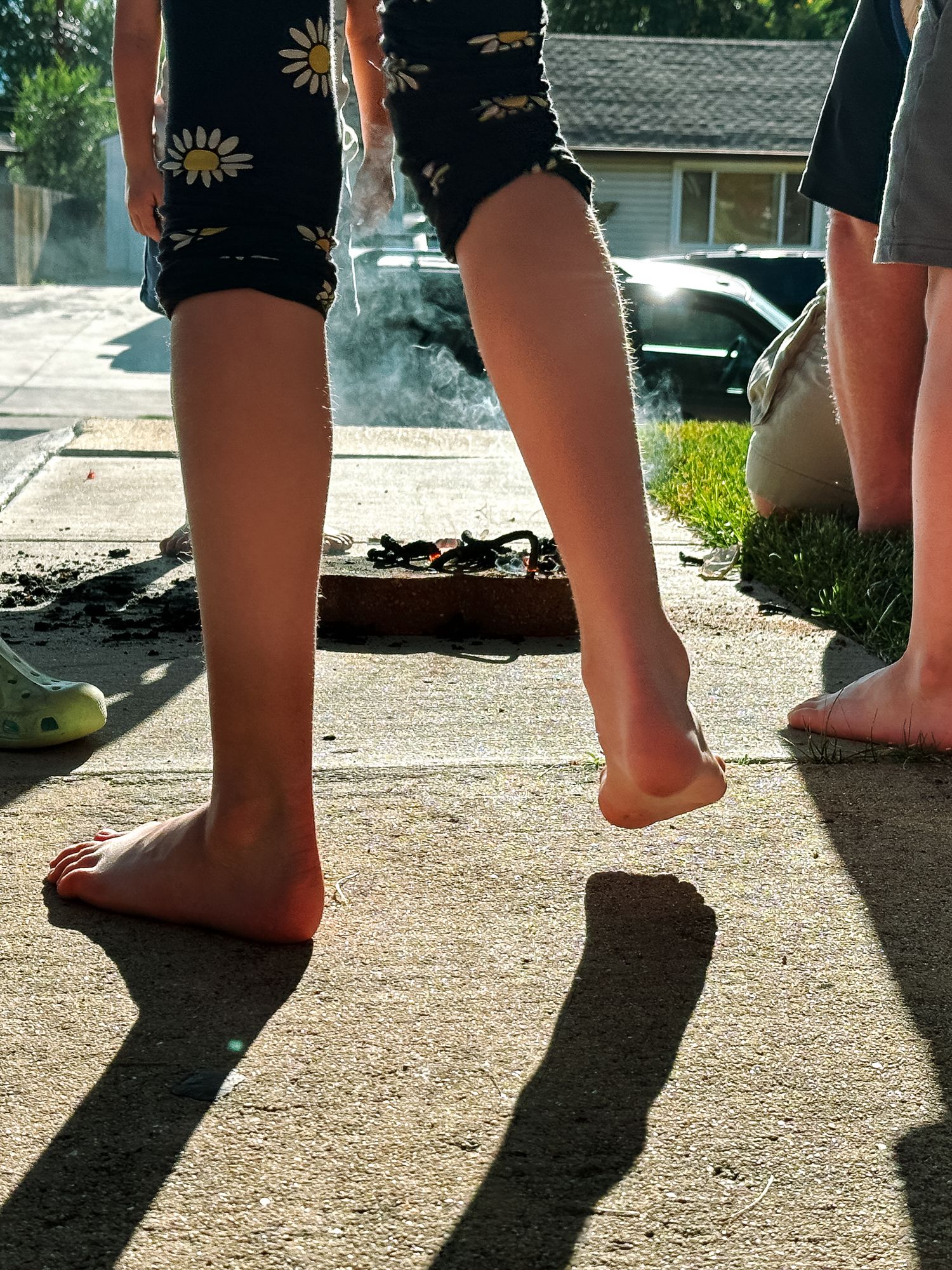 Close up of child's feet with fourth of July snake fireworks in background.
