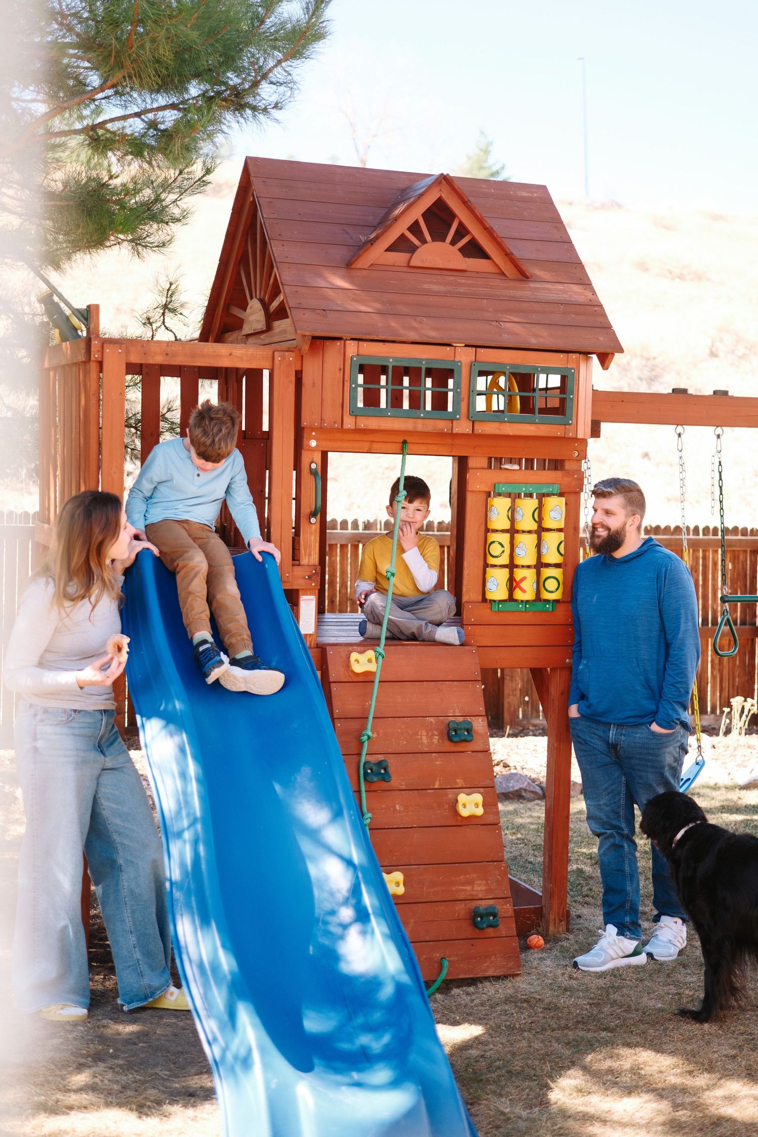 Family of four playing on backyard playground.