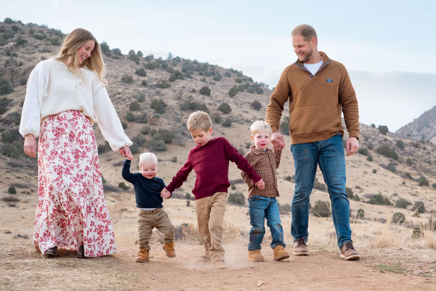 Family of five all holding hands, mother, then three sons, then father, walking down Mt Falcon East Trailhead.